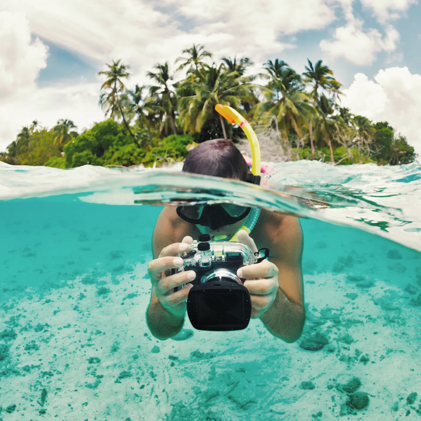 Un plongeur muni d'un tuba et d'un appareil photo sous-marin prend des photos juste au-dessus de la surface de l'eau sur une île tropicale. Un plongeur muni d'un tuba et d'un appareil photo sous-marin prend des photos juste au-dessus de la surface de l'eau sur une île tropicale.