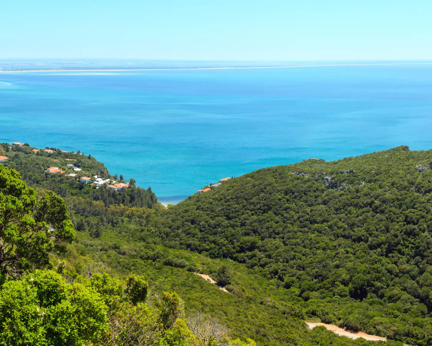 Panoramablick über den Naturpark Arrábida mit grünen Hügeln, türkisblauem Atlantik und der portugiesischen Küste.
