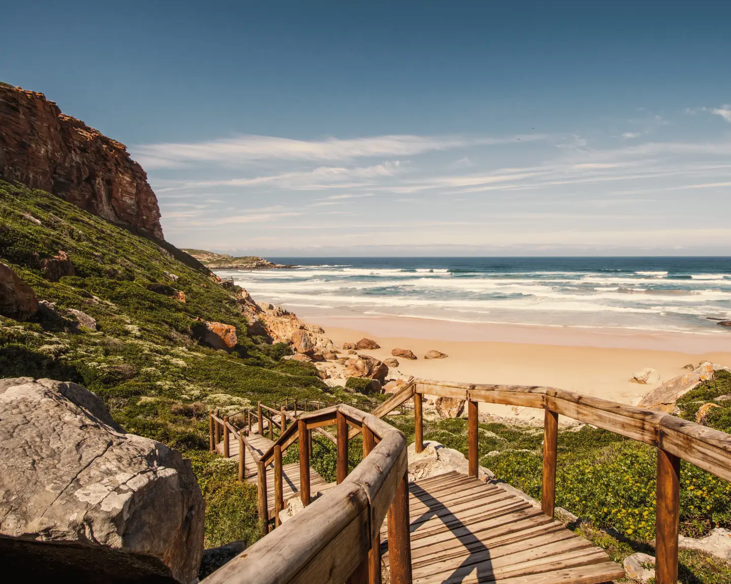 Una escalera de madera baja a la playa de Robberg, una reserva natural en la Ruta Jardín de Sudáfrica.