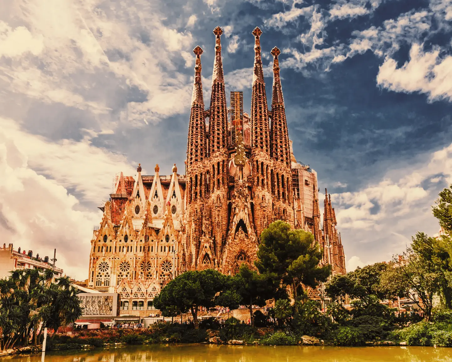La catedral de la Sagrada Familia contra un cielo con nubes bajo el sol.