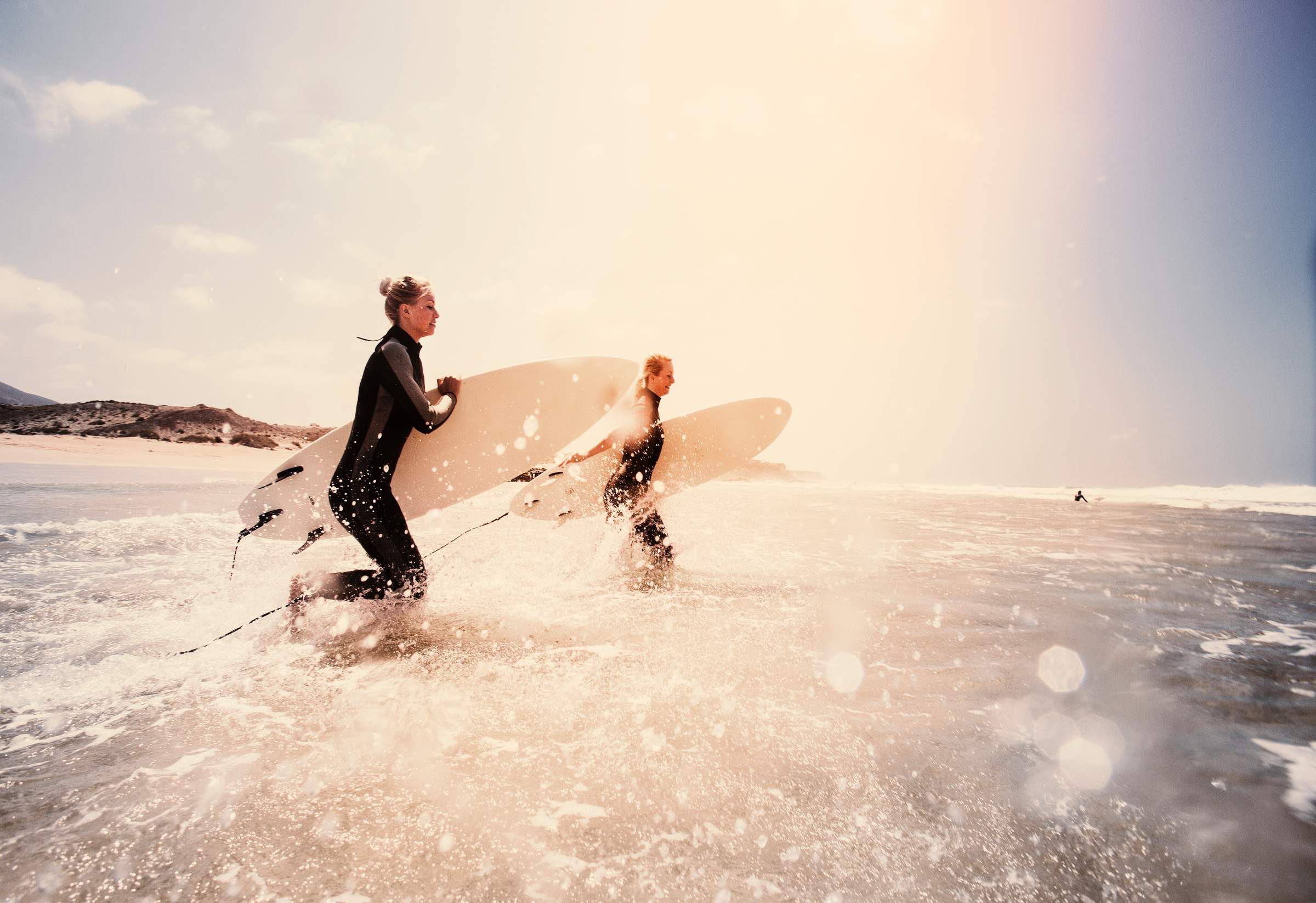 Dos personas sostienen una tabla de surf en el mar.