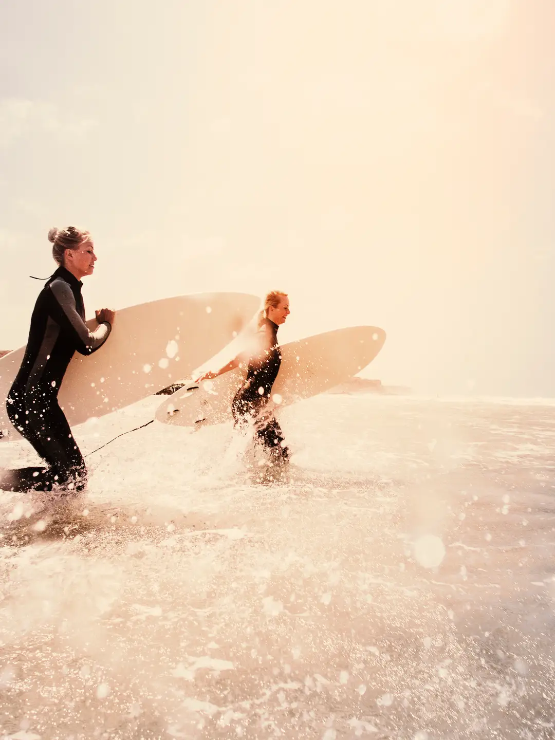 Dos mujeres se adentran en el mar con sus tablas de surf.