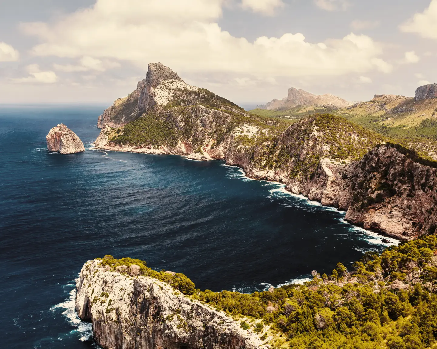 Breathtaking coastal landscape of Mallorca with rocky cliffs and deep blue sea beneath a bright sky.