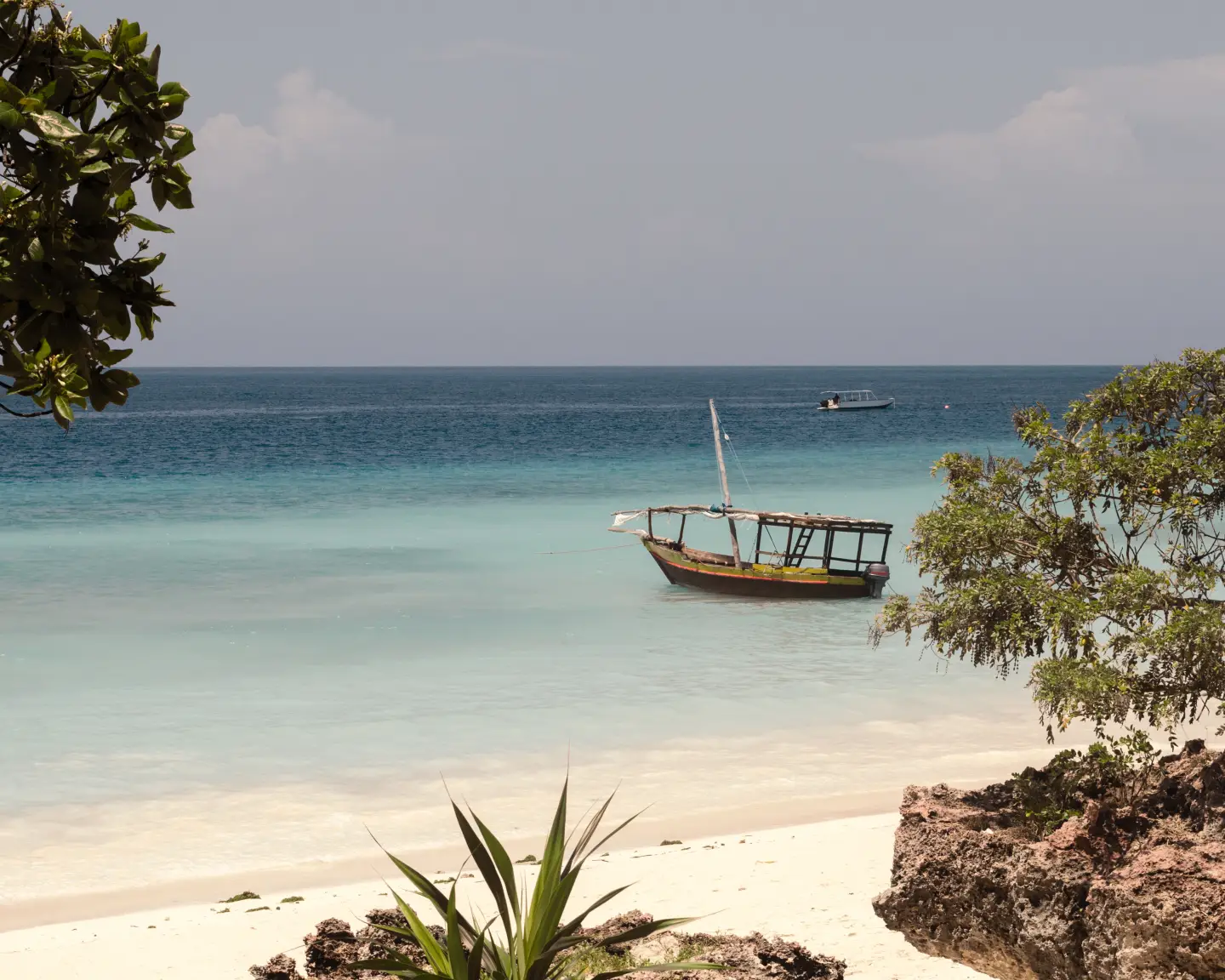 Holzboot auf türkisfarbenem Wasser in Sansibar, Tansania, Afrika