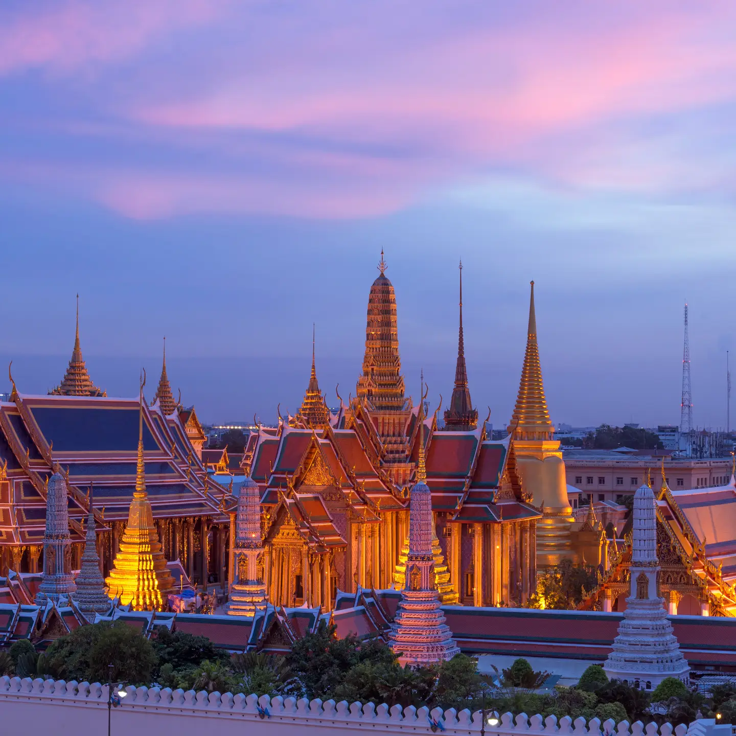 Vista nocturna del Gran Palacio iluminado en Bangkok, Tailandia, bajo un cielo vespertino lleno de color.