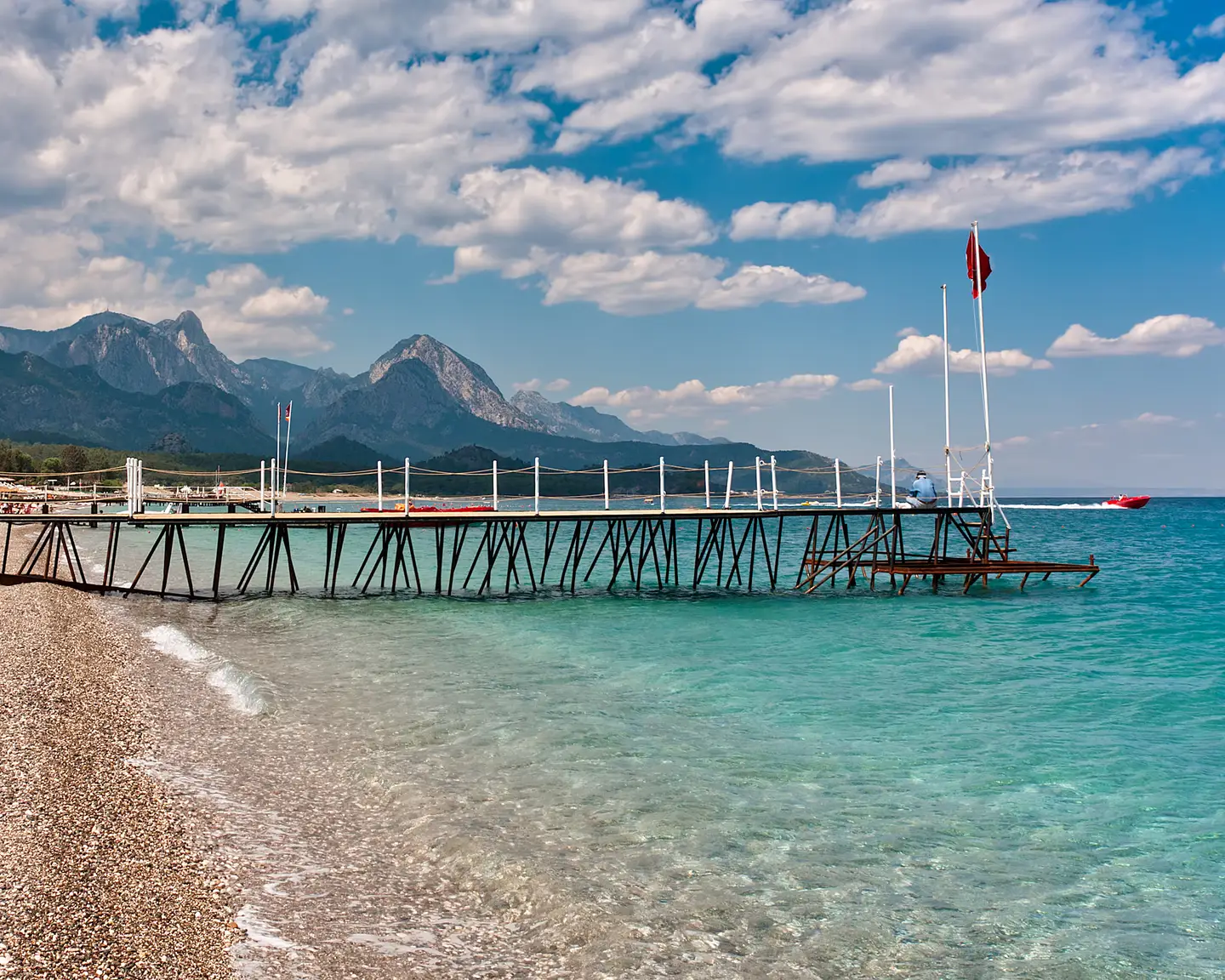 Pequeño embarcadero de madera en una playa de piedras con agua de color turquesa en el popular complejo vacacional de Kemer en el mar Mediterráneo en Turquía.