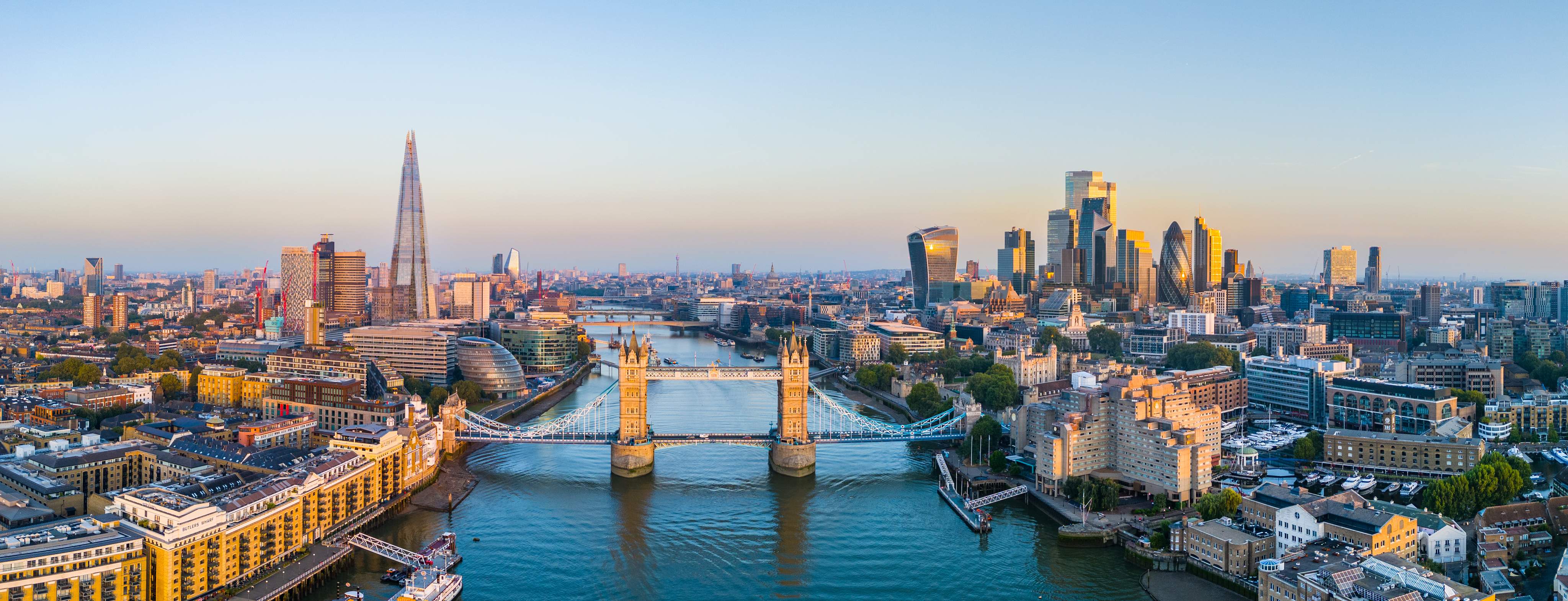 Panoramic view of Tower Bridge, the River Thames and the modern skyline of the City of London with the Shard and the financial district in the evening light.