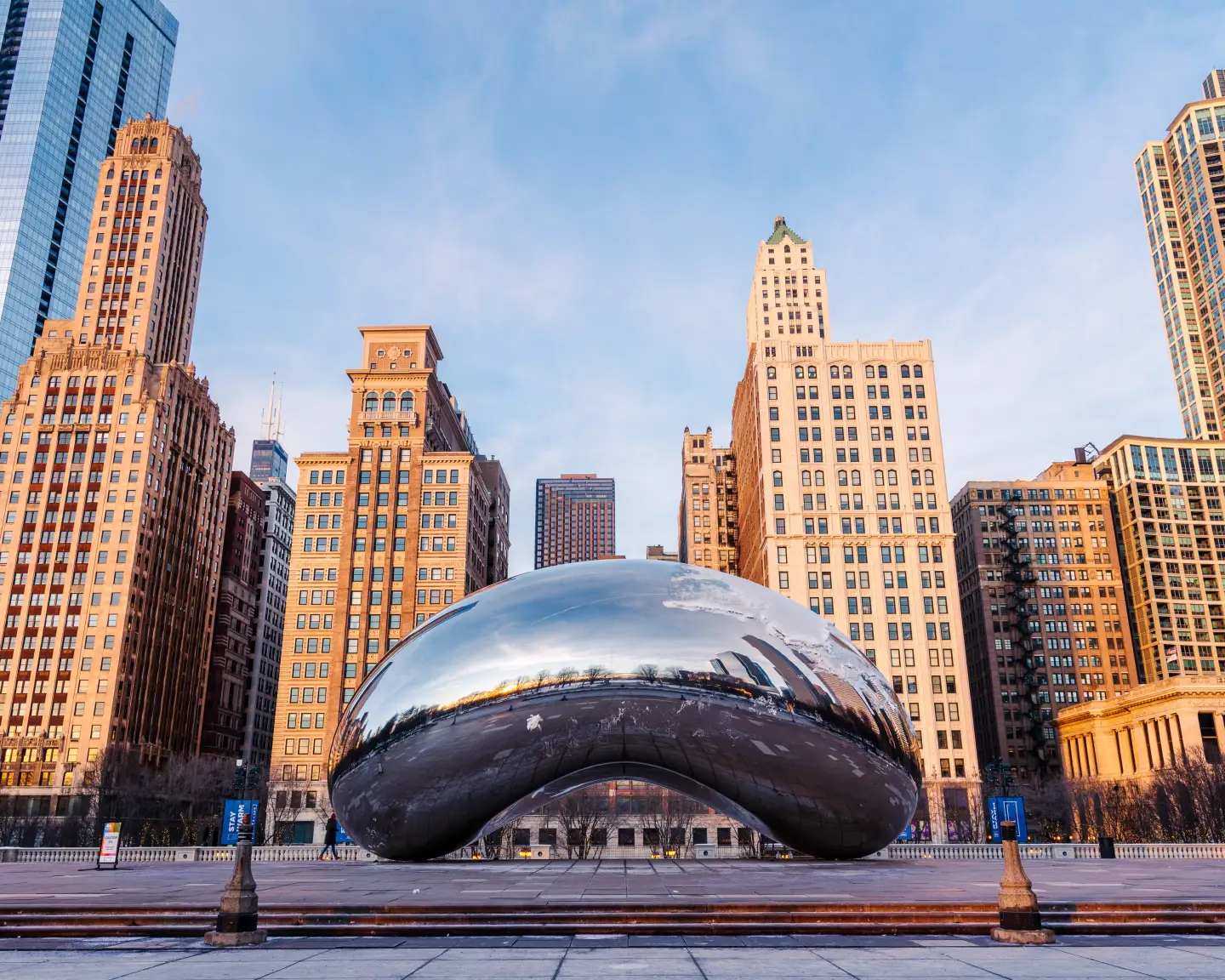 Cloud Gate, auch genannt „The Bean“, im Millennium Park in Chicago, umgeben von Hochhäusern der Skyline bei Sonnenaufgang.