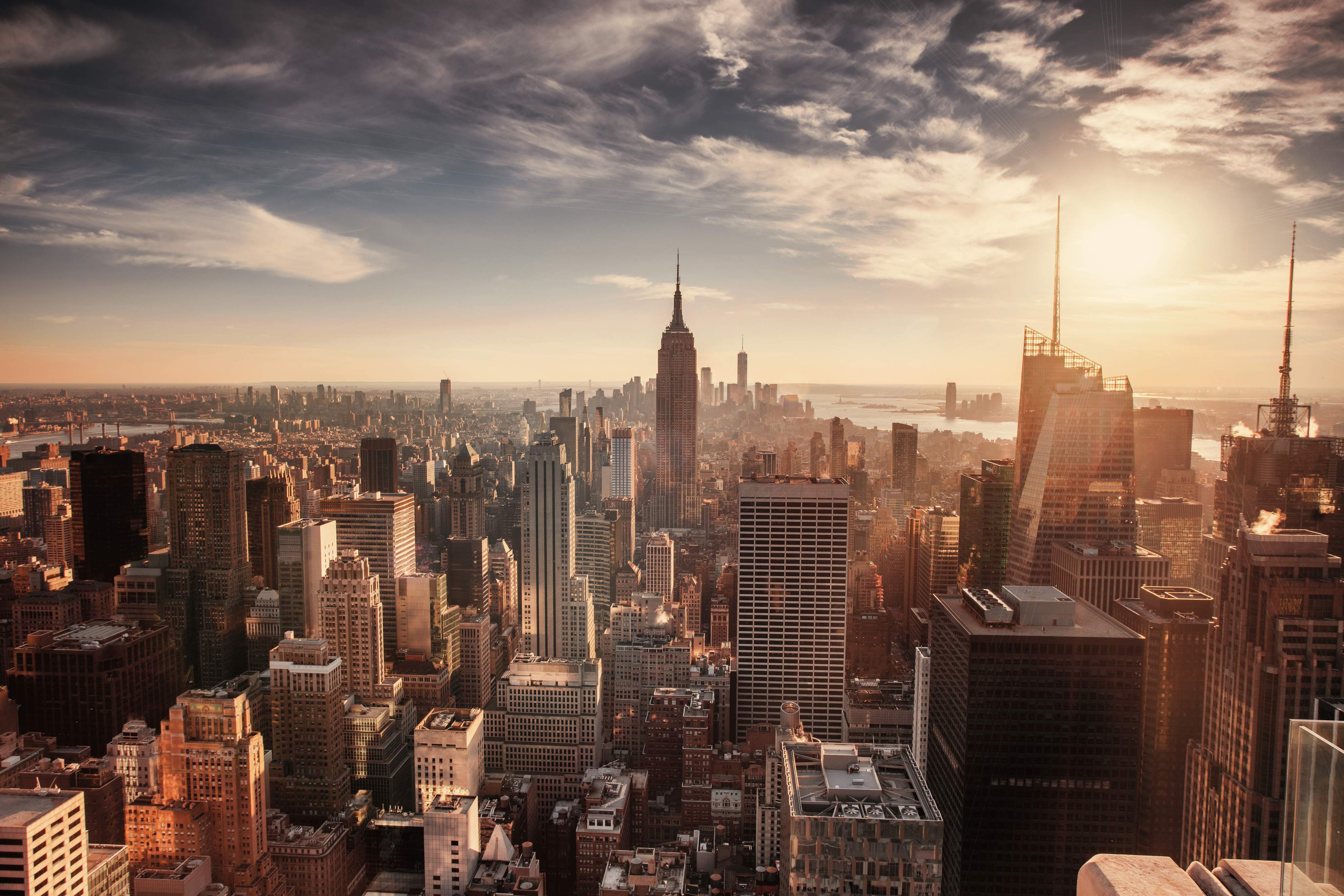Panoramic view of the skyline of Manhattan, New York City, at sunrise with the Empire State Building in the centre and One World Trade Center in the background.