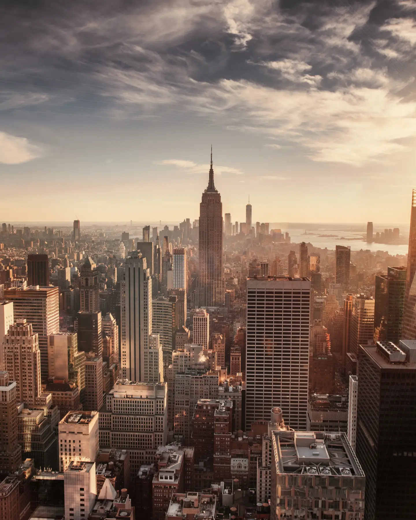 Vista panoramica dello skyline di Manhattan, New York City, all'alba, con l'Empire State Building al centro e One World Trade Center sullo sfondo.