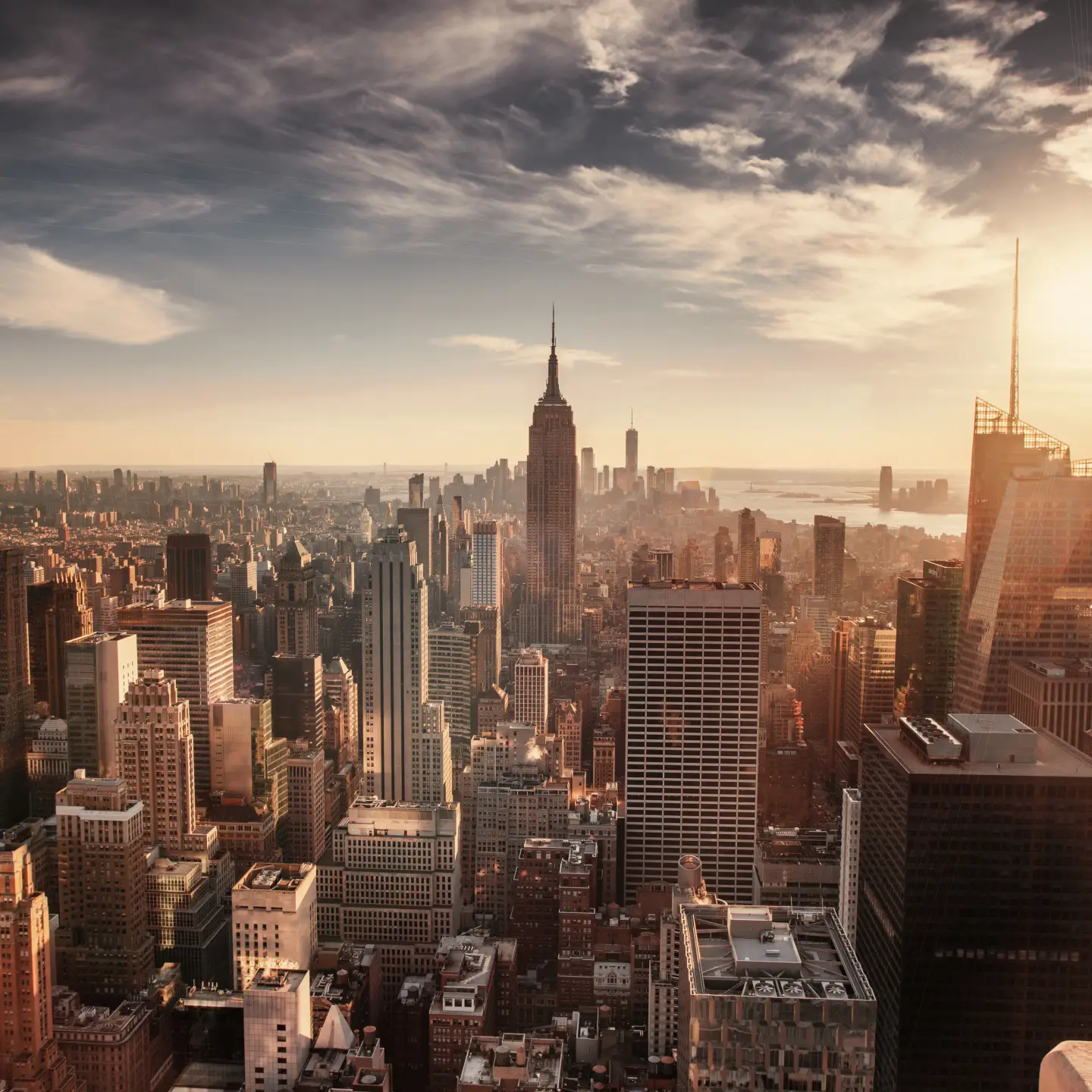 Vista panoramica dello skyline di Manhattan, New York City, all'alba, con l'Empire State Building al centro e One World Trade Center sullo sfondo.
