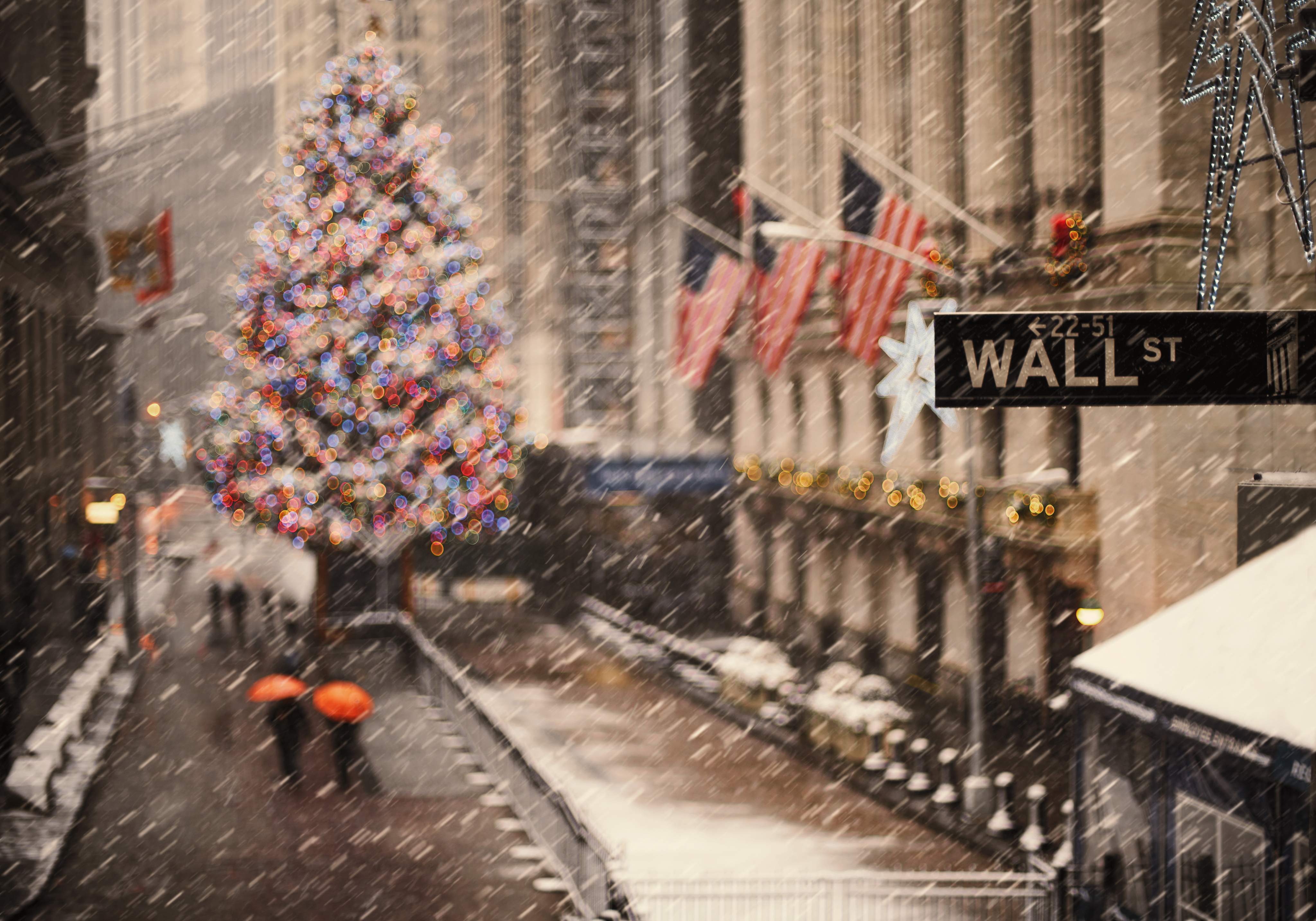 View of Wall Street in New York with a lit-up Christmas tree in the snow during the holiday season,