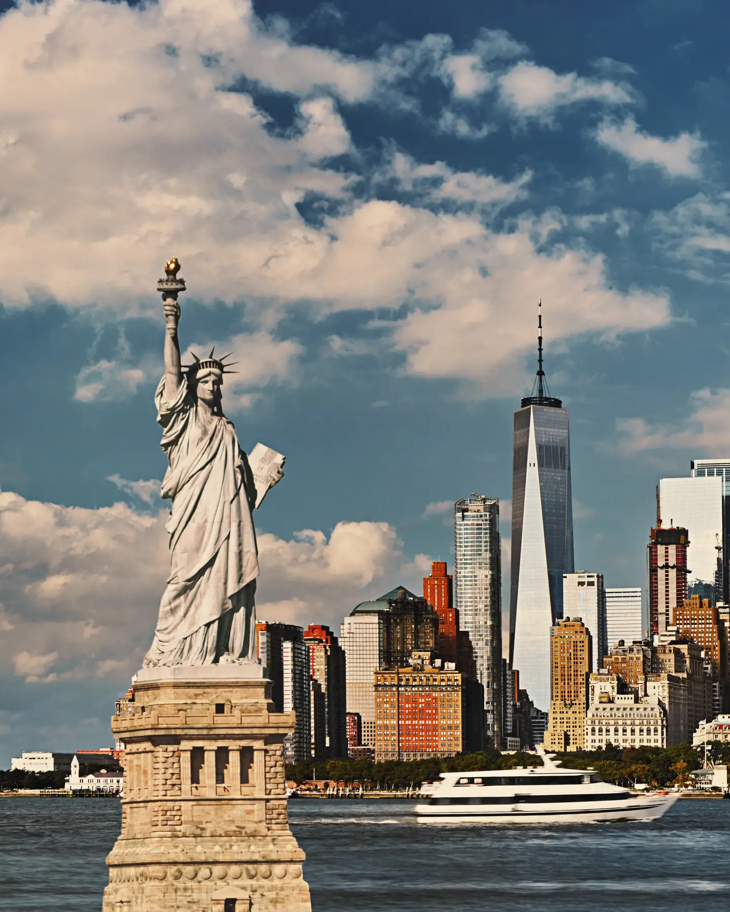 La Estatua de la Libertad de Nueva York delante del perfil urbano de Manhattan bajo un cielo azul claro.