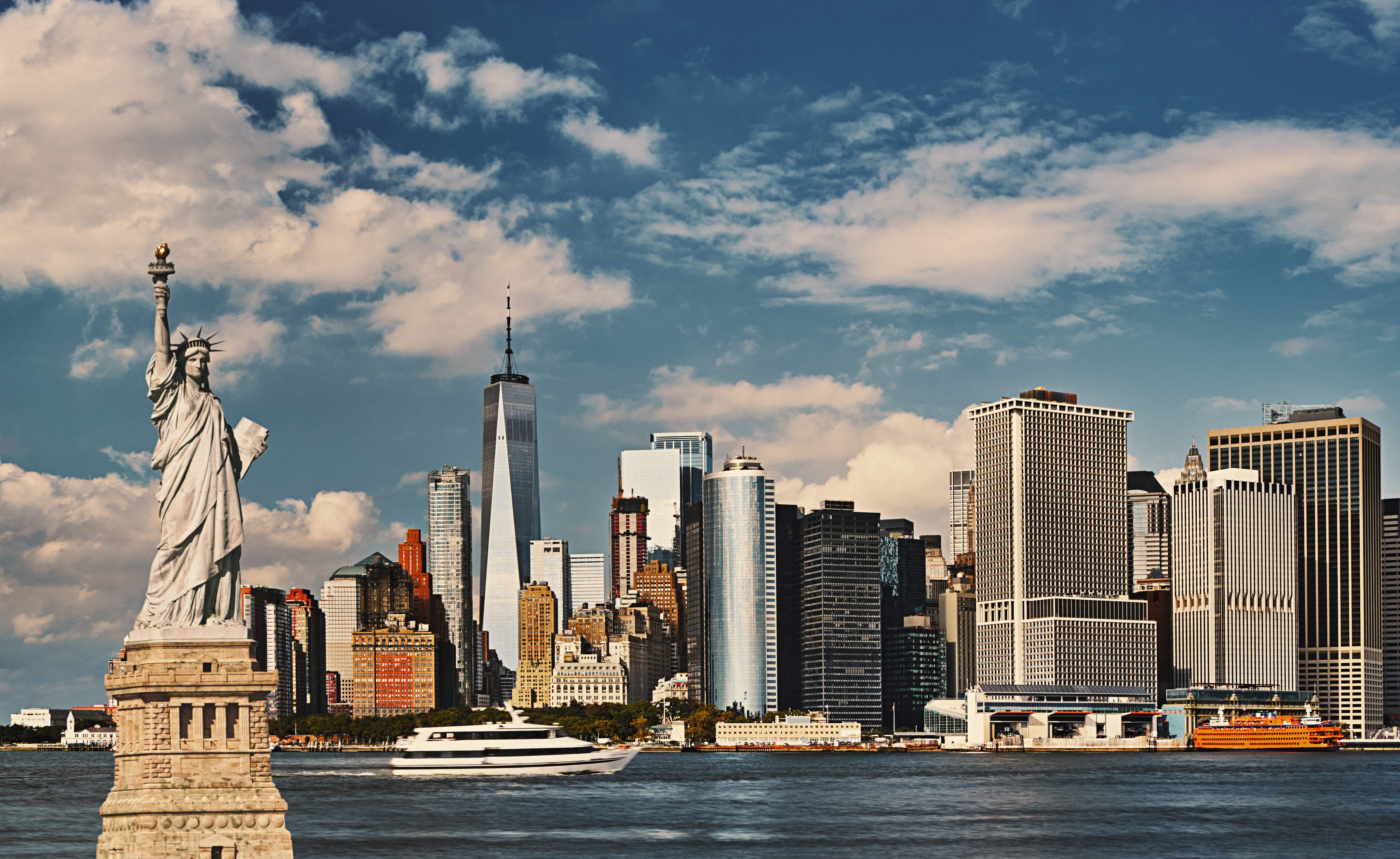 A New York-i Szabadság-szobor a manhattani látkép előtt, tiszta kék ég alatt.