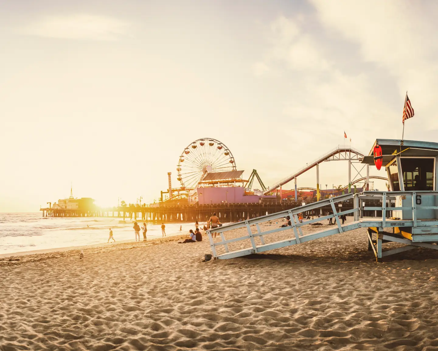 Vista de la playa en el muelle de Santa Mónica con la noria al fondo al atardecer.