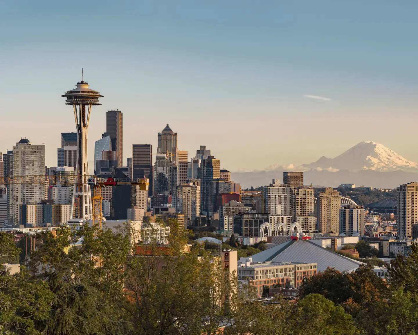 Pohled na panorama Seattlu ve státě Washington s věží Space Needle v popředí a horou Mount Rainier v pozadí.