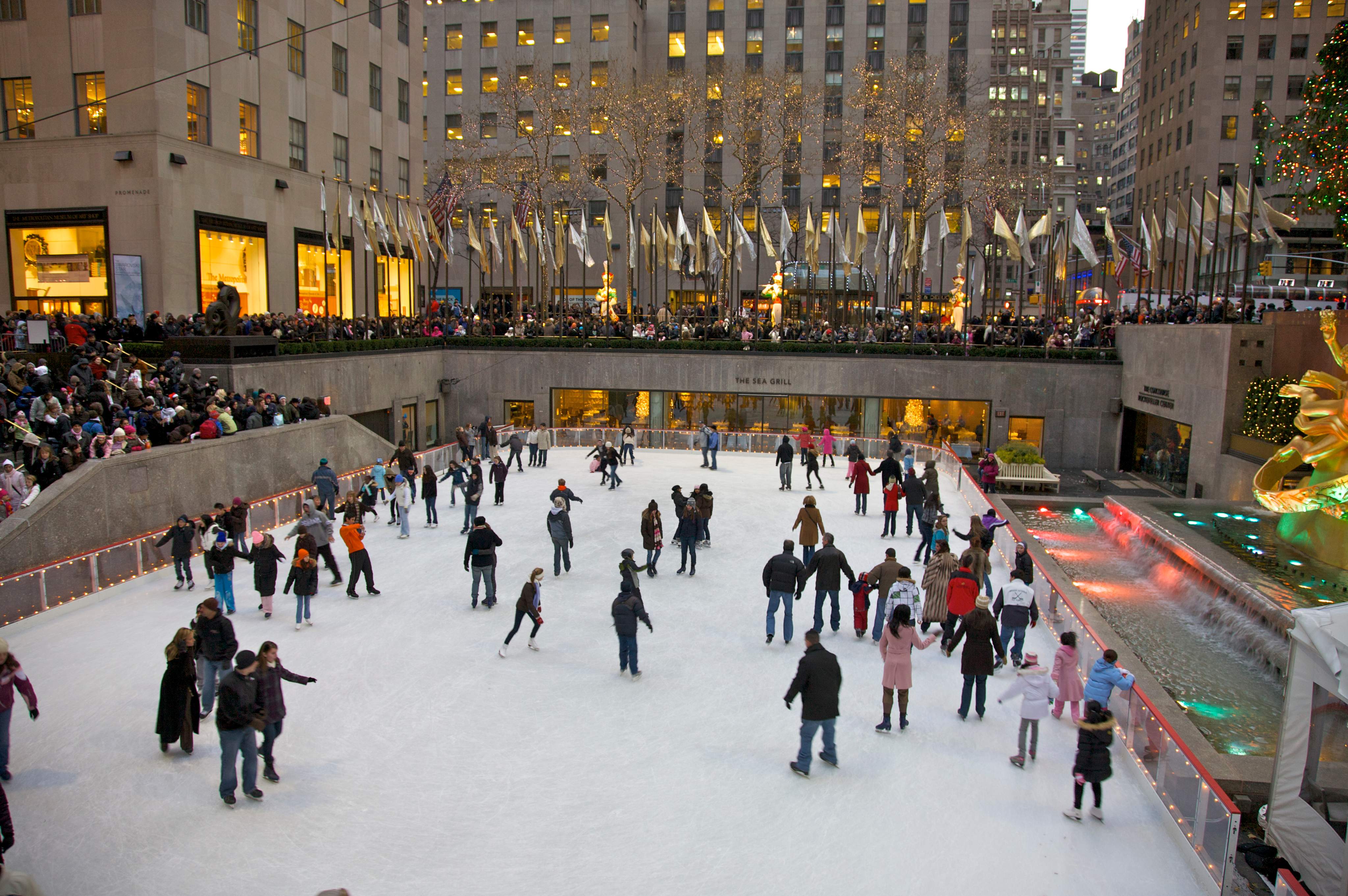 Menschen laufen Schlittschuh auf der berühmten Eislaufbahn am Rockefeller Center, umgeben von festlicher Beleuchtung und der winterlichen Atmosphäre in New York City.