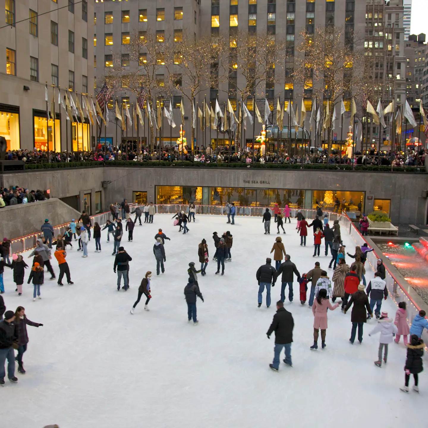 Menschen laufen Schlittschuh auf der berühmten Eislaufbahn am Rockefeller Center, umgeben von festlicher Beleuchtung und der winterlichen Atmosphäre in New York City.