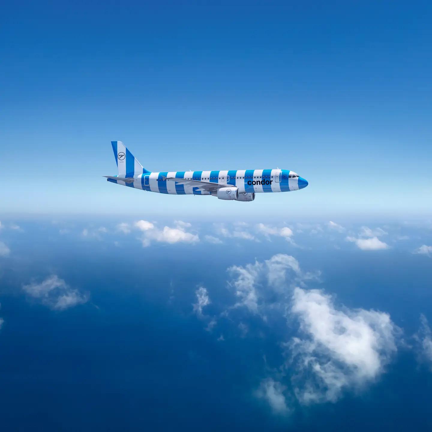 Un Airbus A320-200 de Condor con rayas verdes y blancas sobre un cielo azul claro, con finas nubes blancas debajo.