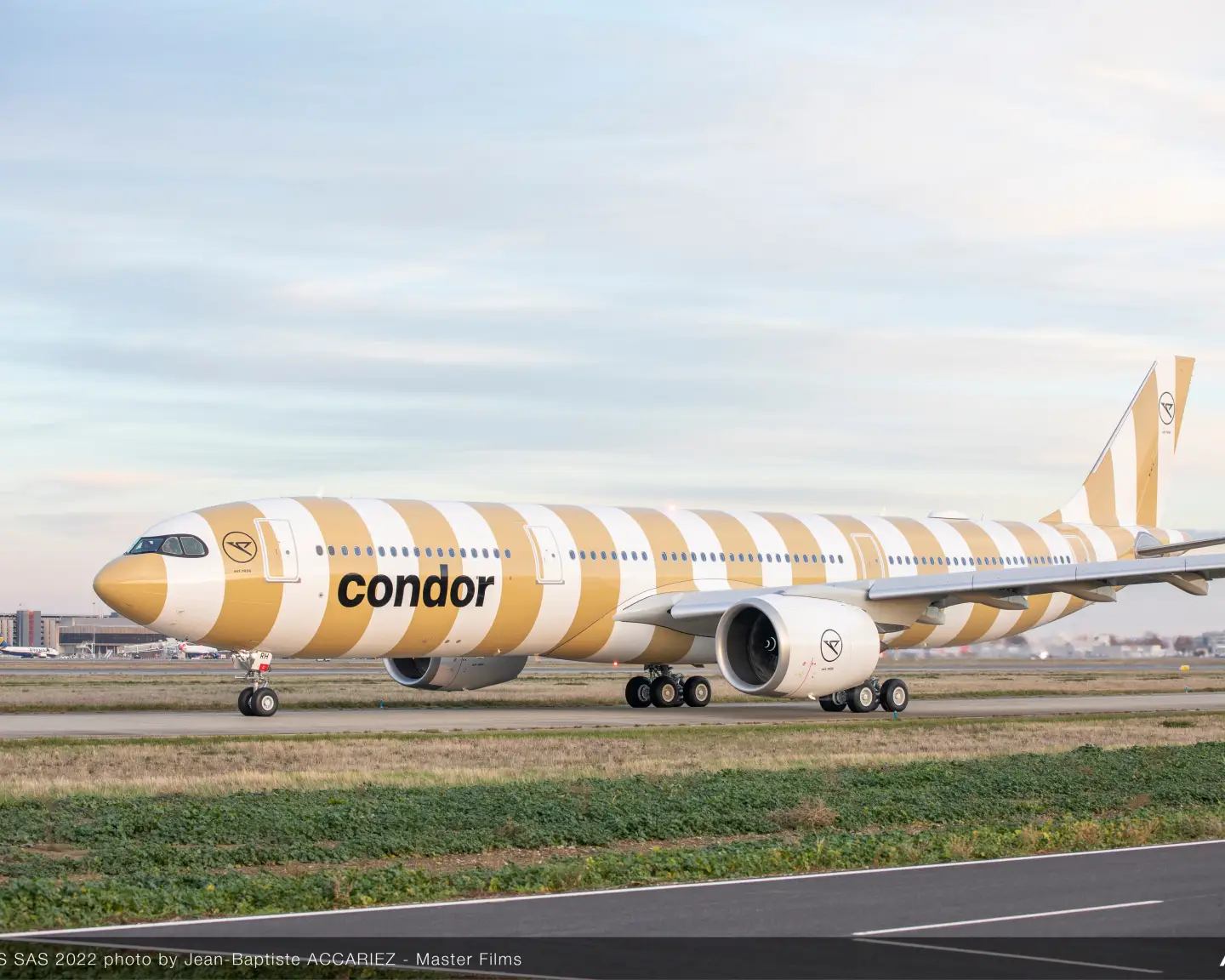 A beige-striped Airbus A330neo taxis across the runway