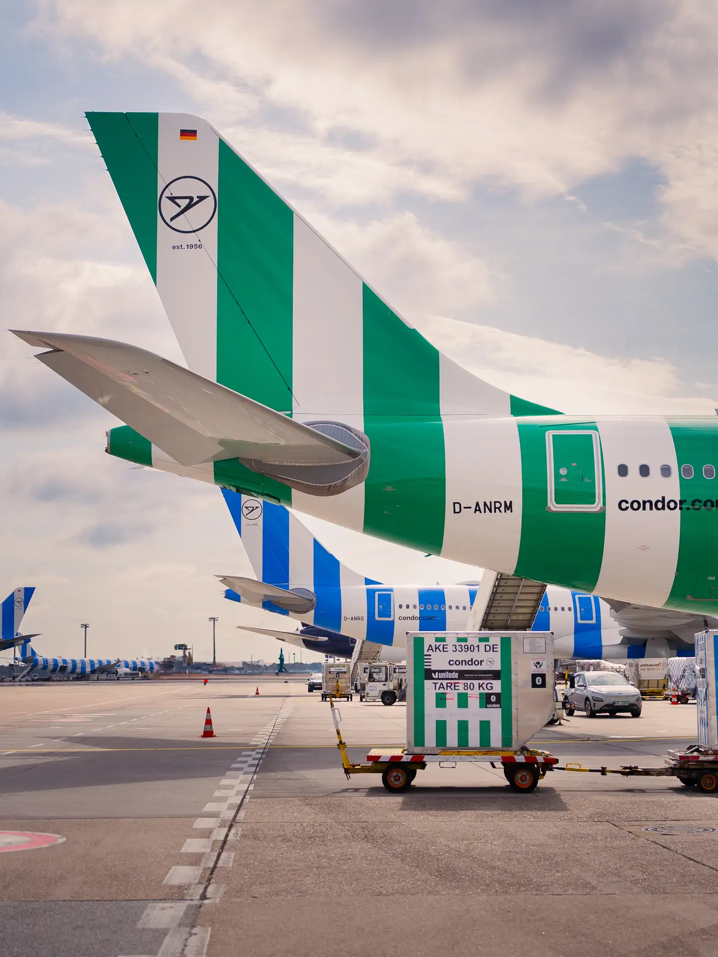 Dos contenedores de carga delante de un A330neo de Condor en color Island.