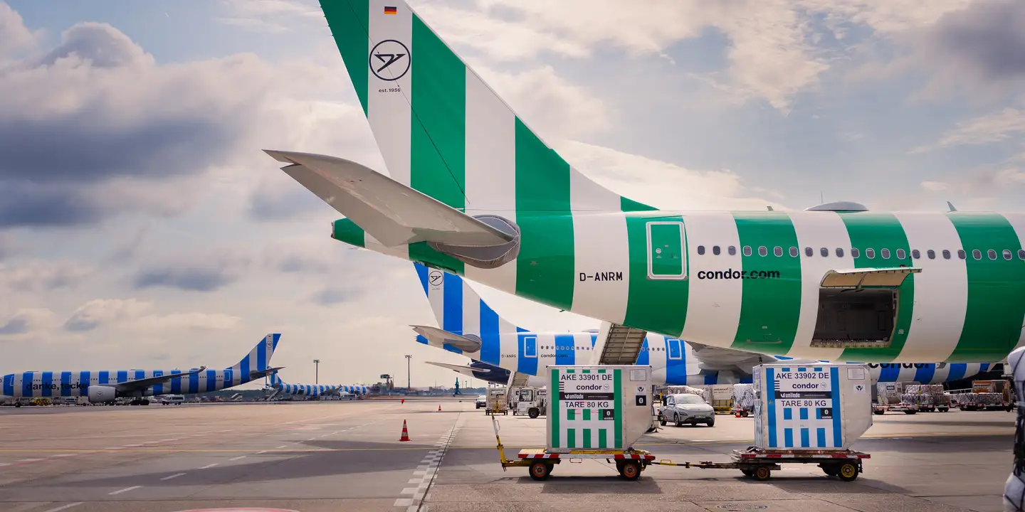 Dos contenedores de carga delante de un A330neo de Condor en color Island.