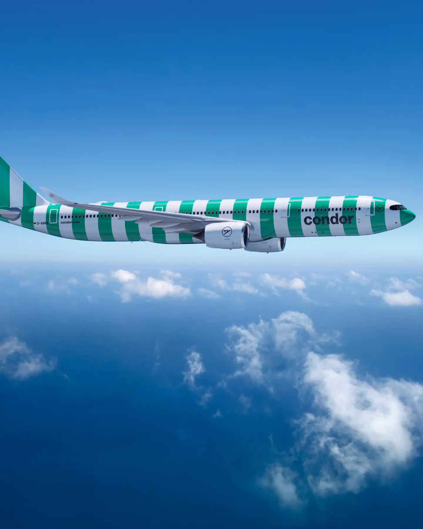 Een Condor A330neo in de kleur Island (groen) vliegt boven de wolken tegen een heldere blauwe lucht.