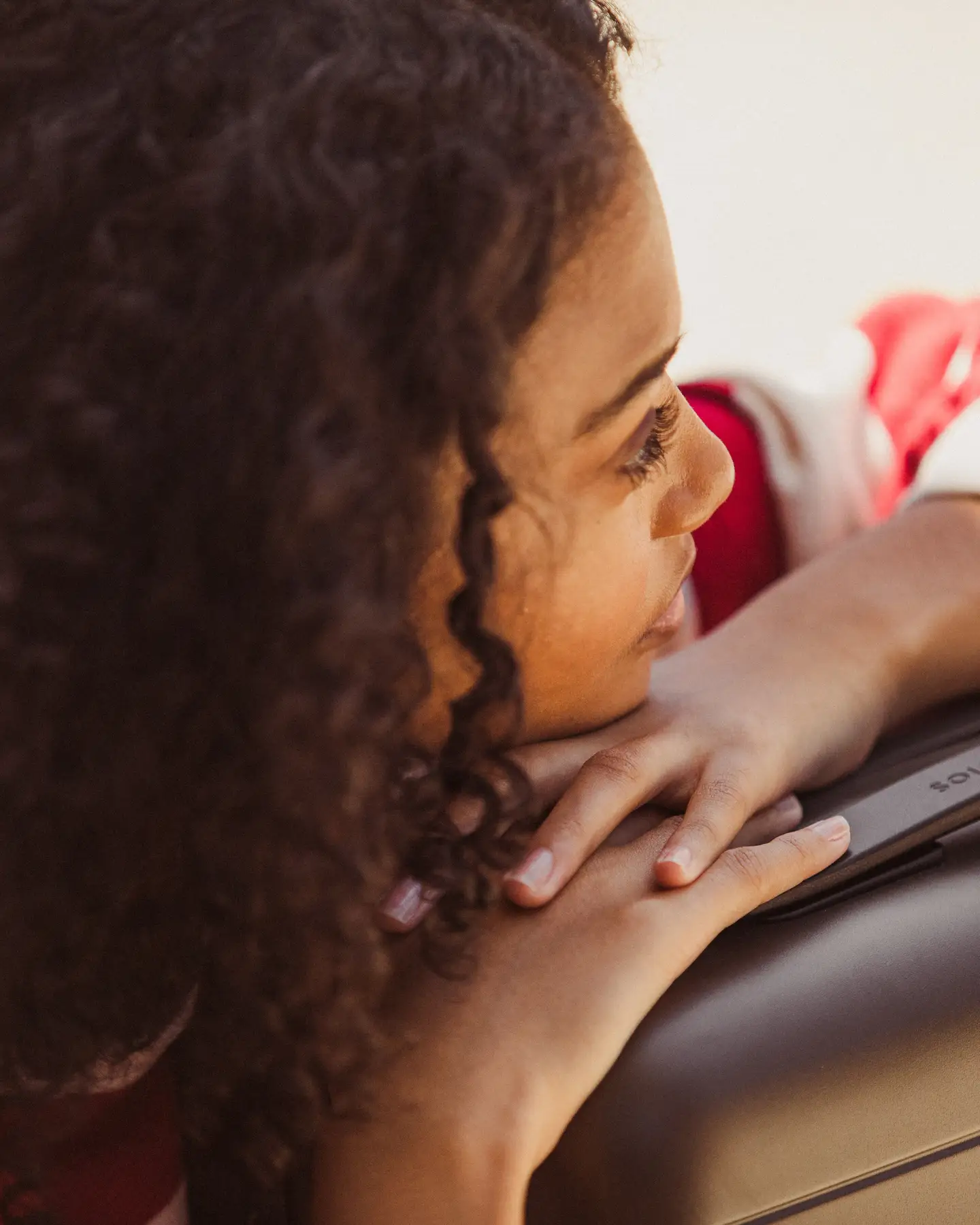 Una mujer está apoyada en su maleta.