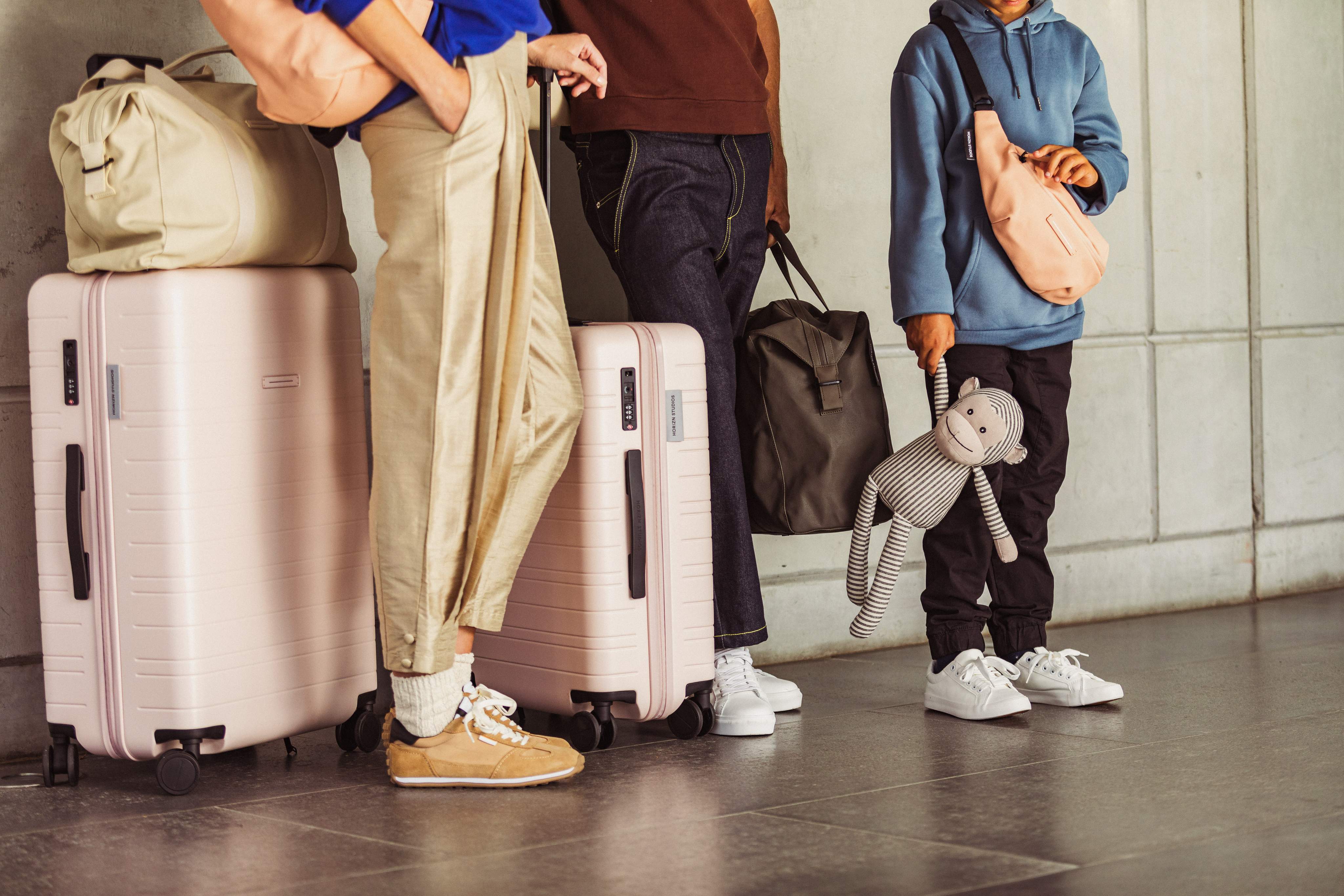 Un groupe de personnes debout avec leurs bagages à l’aéroport.