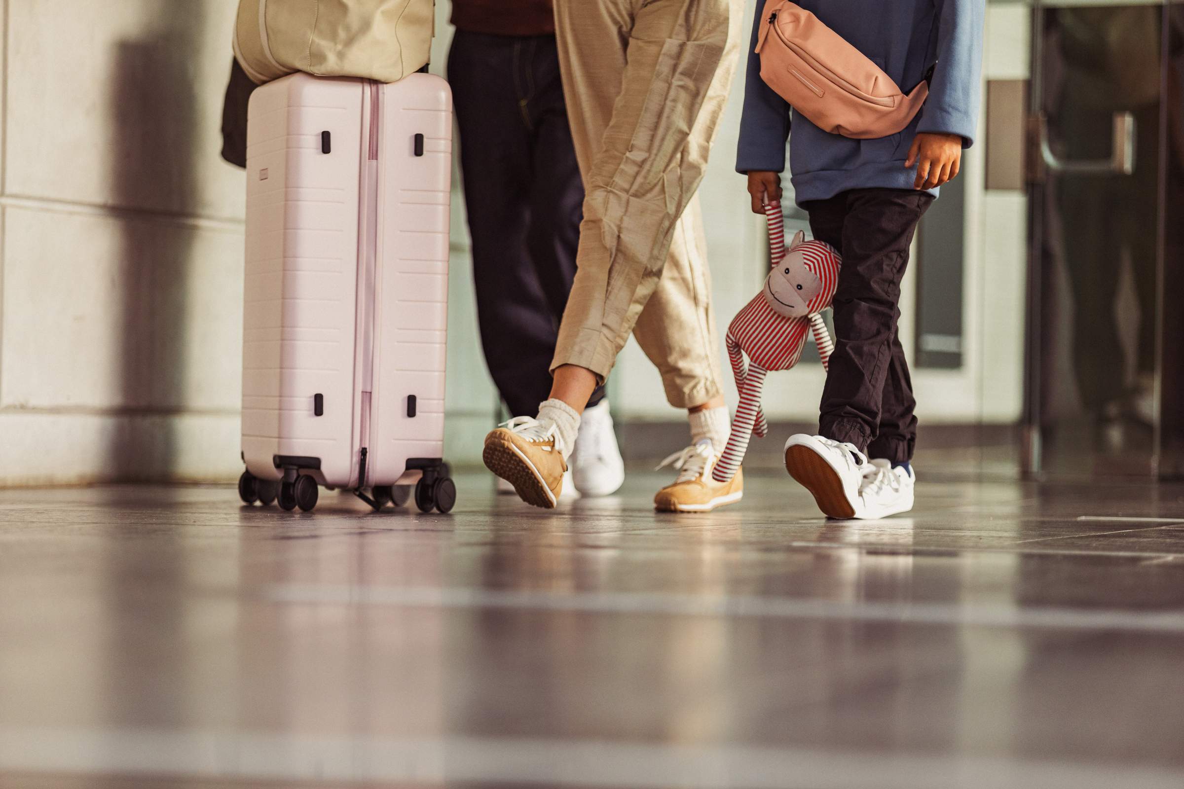 Un grupo de pasajeros con su equipaje, del que solo se ven las piernas y las maletas y un niño que sostiene un peluche