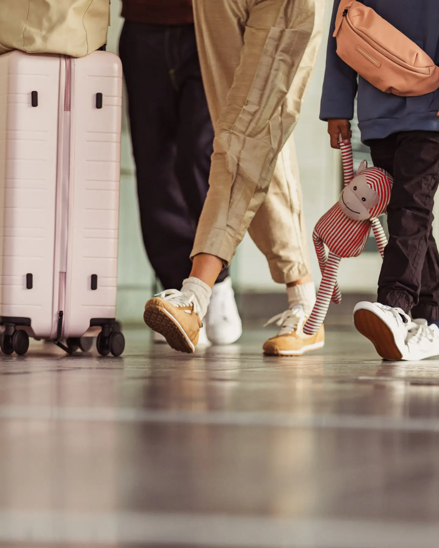 A group of passengers with their baggage, with only their legs and suitcases visible, and a child holding a soft toy