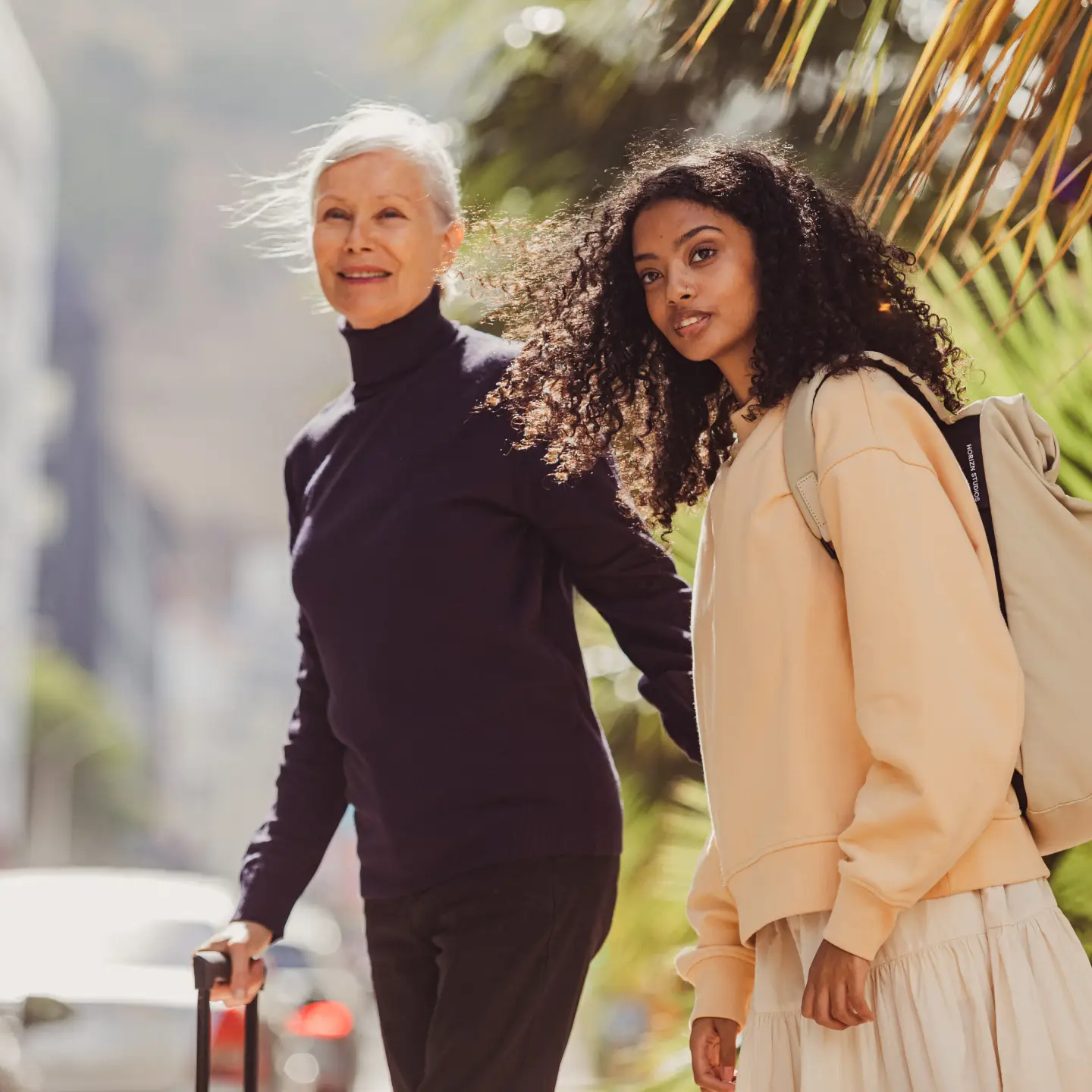 Deux femmes traversent la rue avec leurs valises.