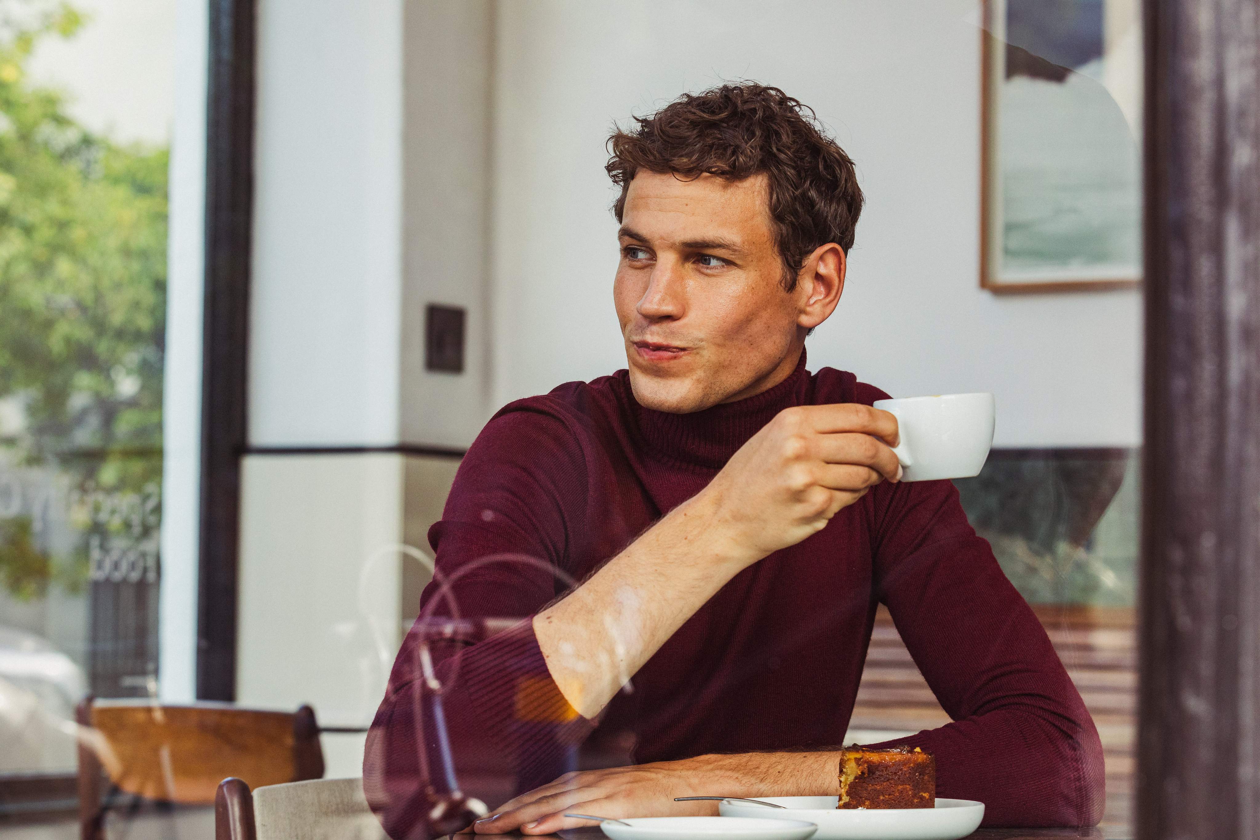 Een man die een kop koffie drinkt tijdens het ontbijt in een hotel.