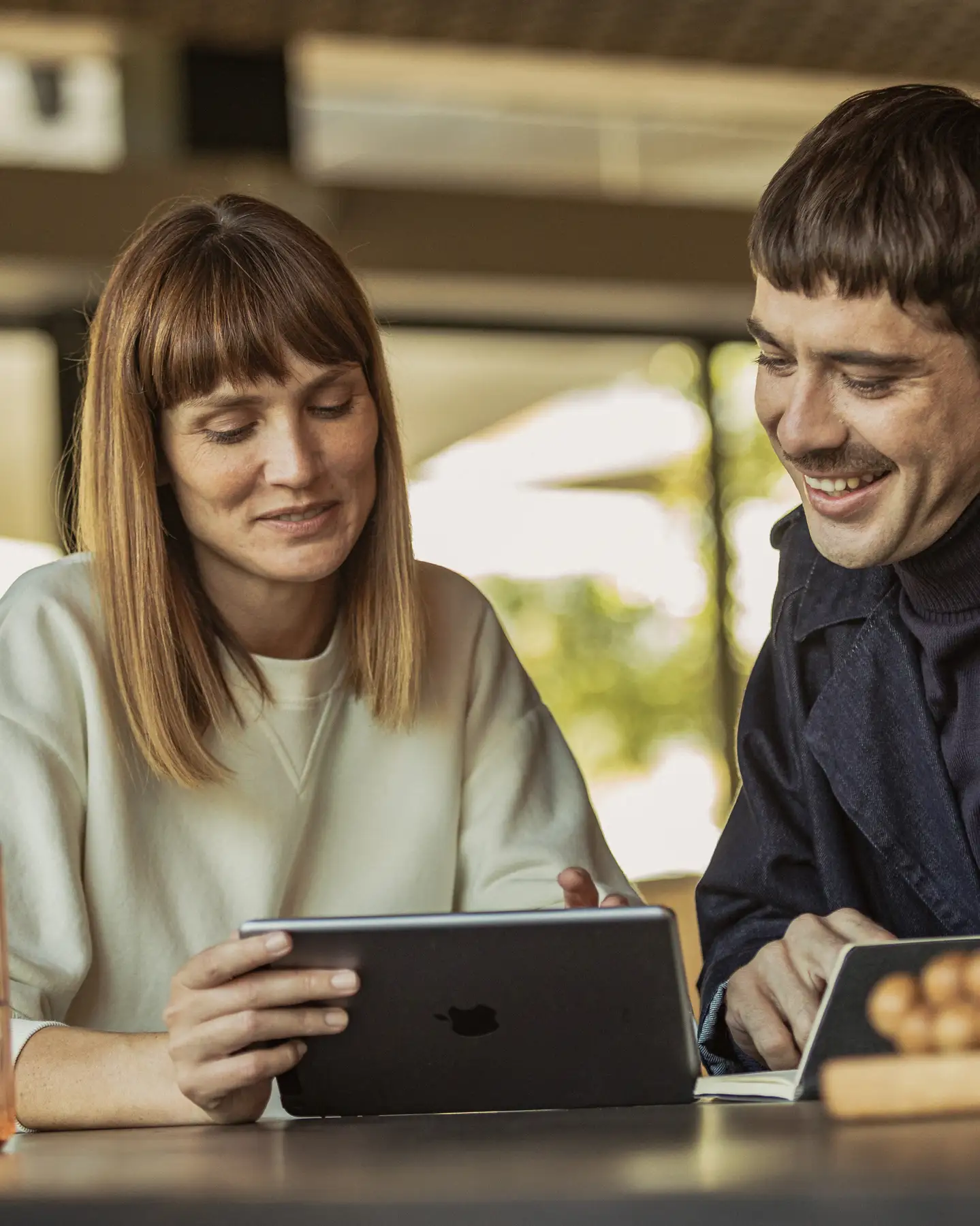 Un chico y una chica sentados en una mesa mirando su tableta.