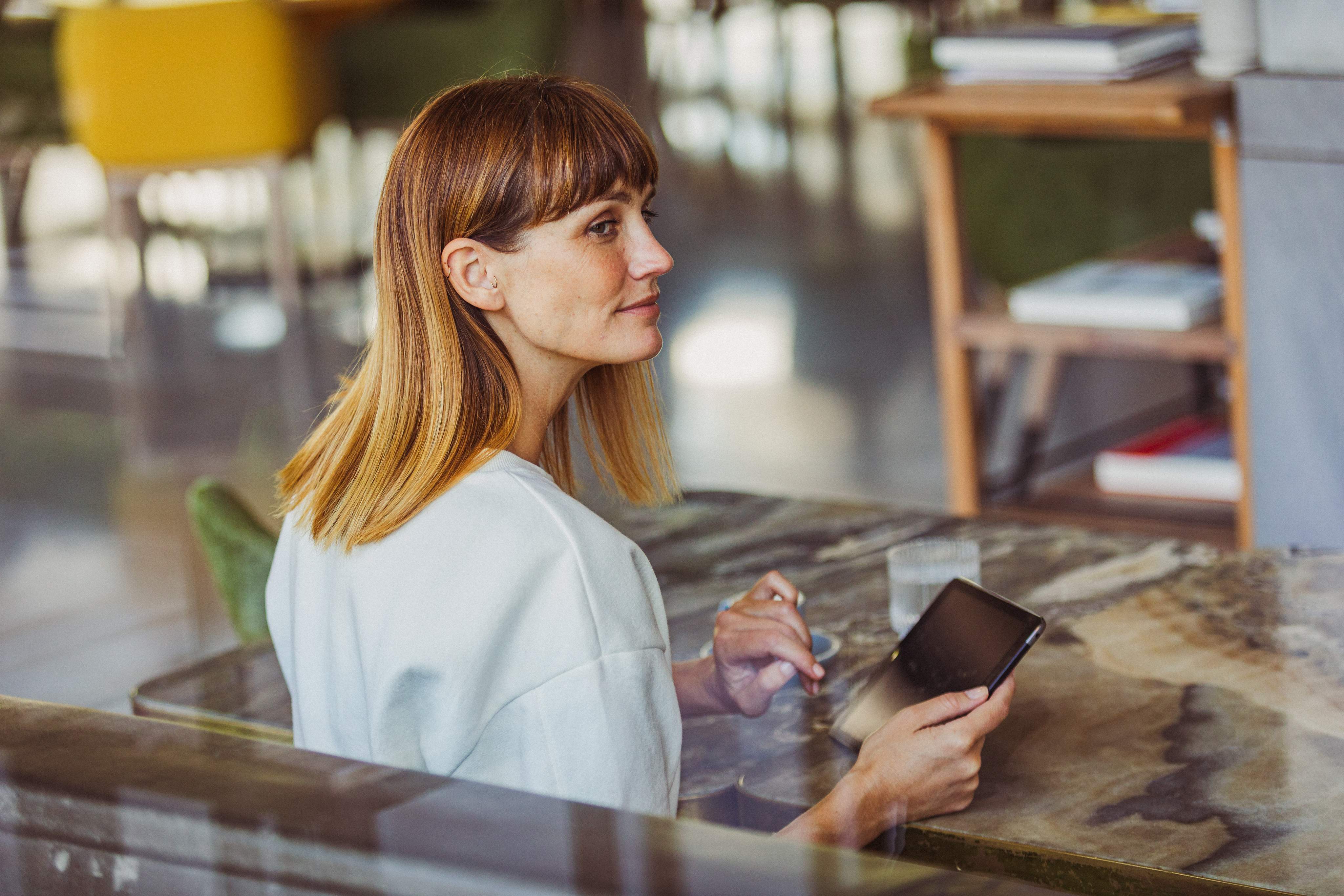 Une femme dans la force de l’âge utilise un smartphone dans un bureau moderne.