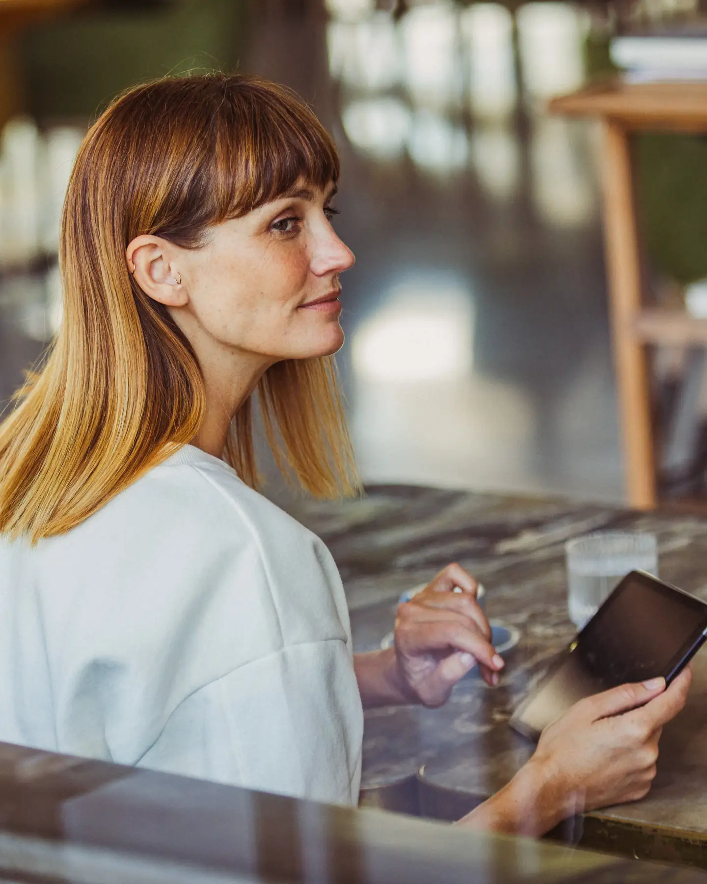 Une femme dans la force de l’âge utilise un smartphone dans un bureau moderne.