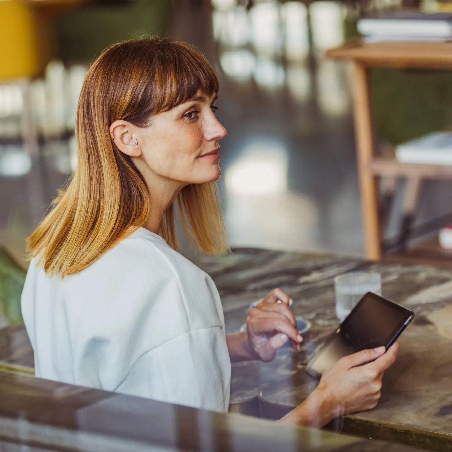 Une femme dans la force de l’âge utilise un smartphone dans un bureau moderne.