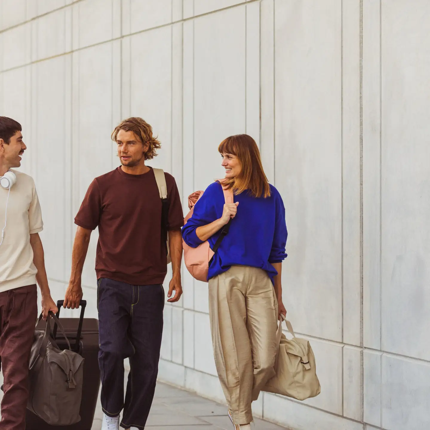 Un groupe d'amis traverse l'aéroport en direction de la porte d'embarquement avec leurs valises.