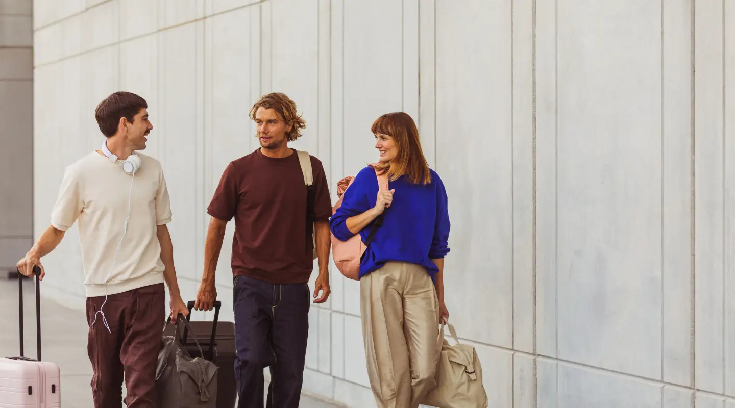 Un groupe d'amis traverse l'aéroport en direction de la porte d'embarquement avec leurs valises.