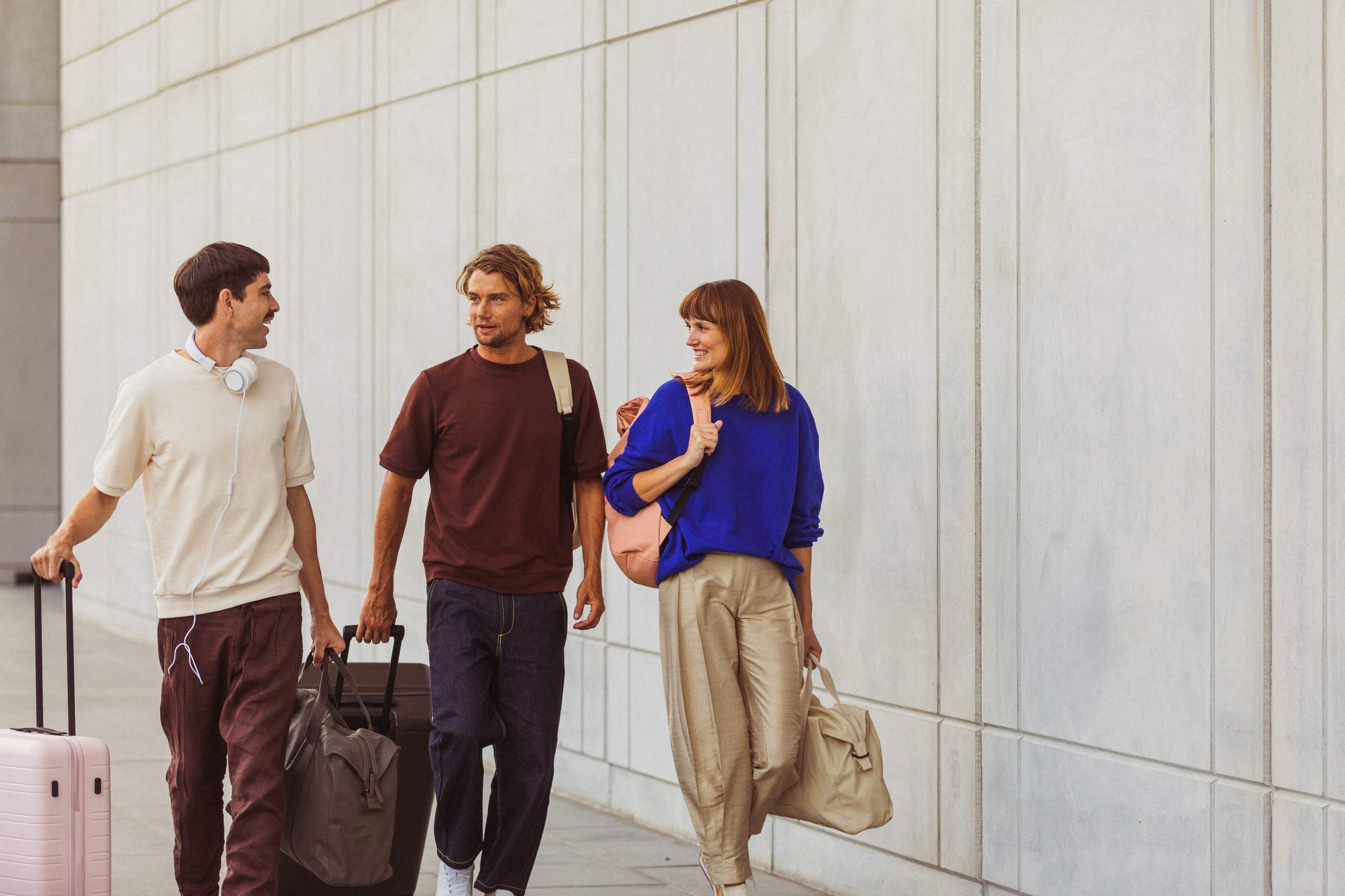 Un grupo de amigos camina por el aeropuerto hacia la puerta de embarque con sus maletas.