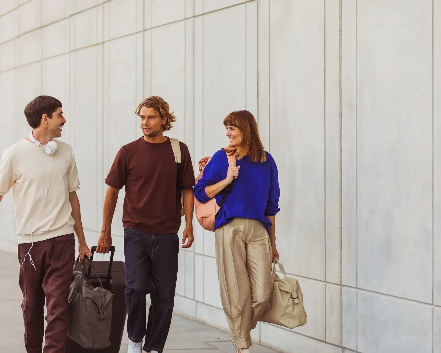 Un grupo de amigos camina por el aeropuerto hacia la puerta de embarque con sus maletas.