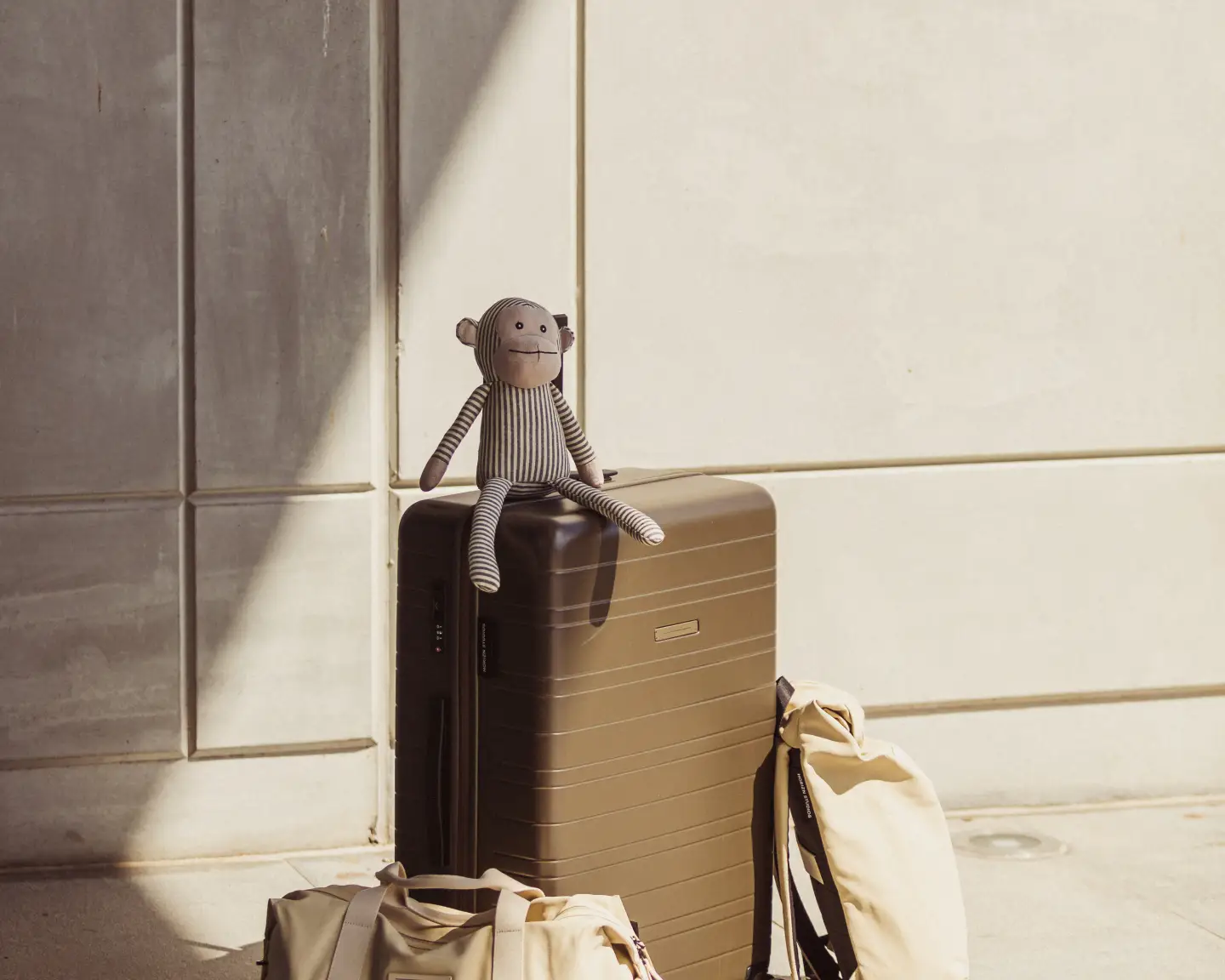 Une peluche est assise sur une valise à l’aéroport.
