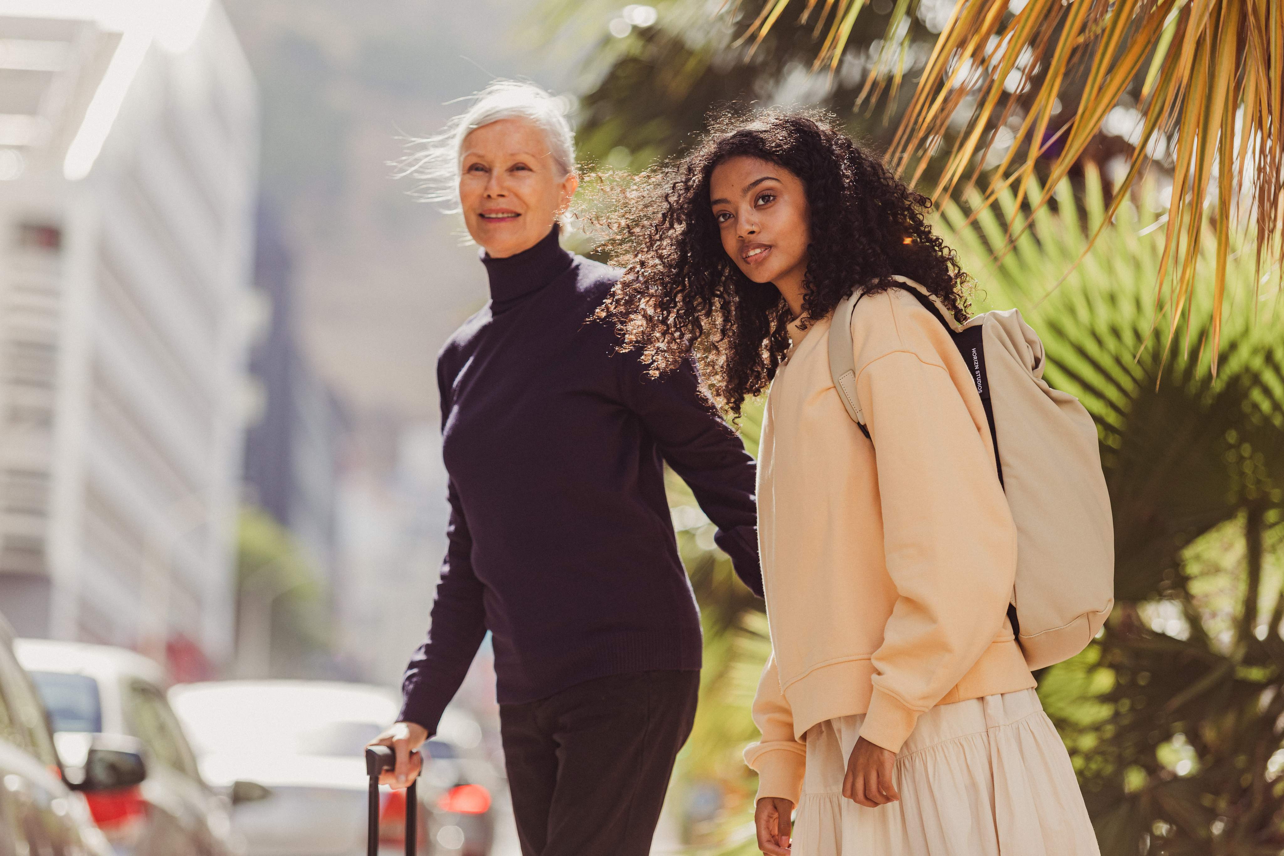 Twee vrouwen steken de straat over met hun koffers.