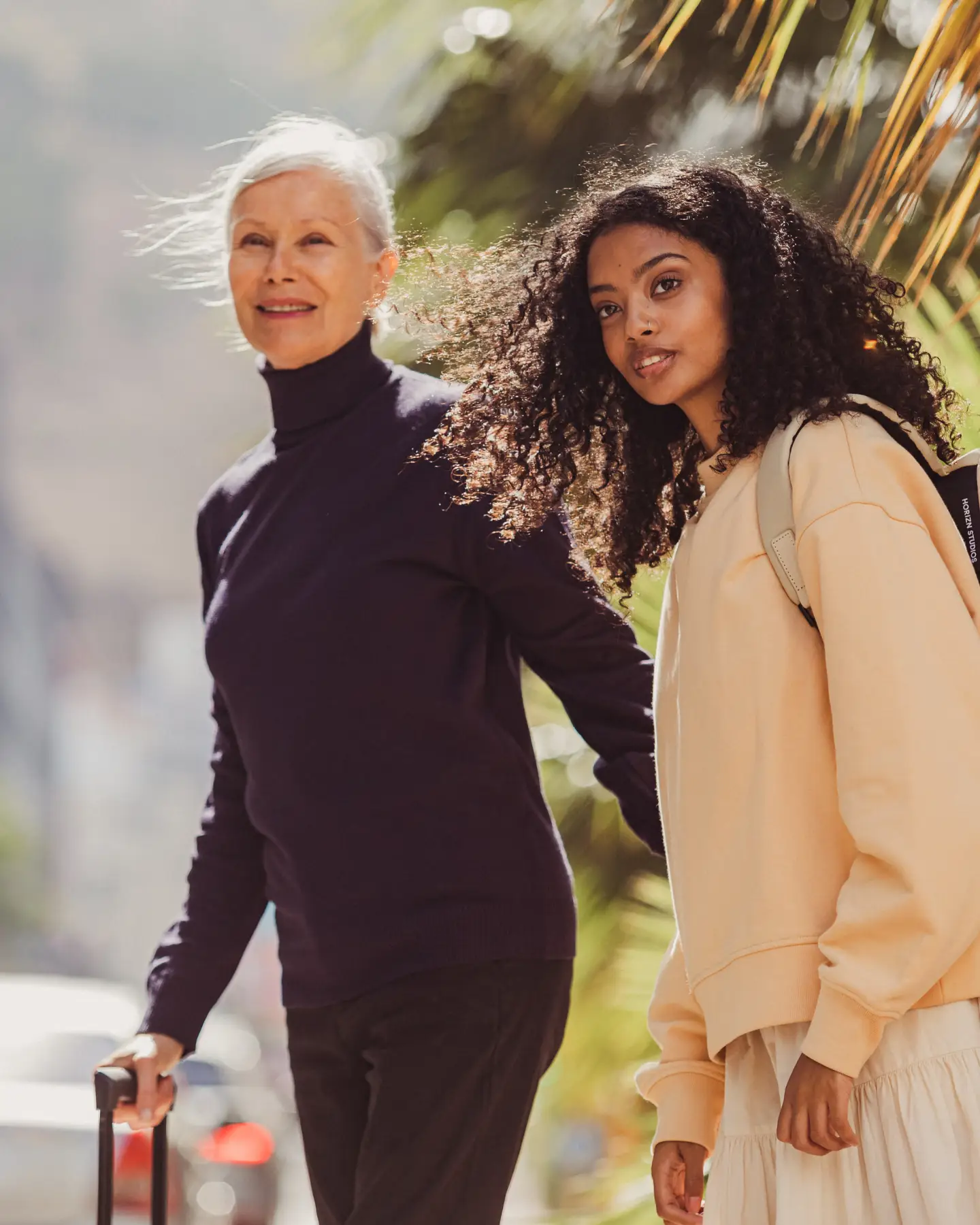 Twee vrouwen steken de straat over met hun koffers.