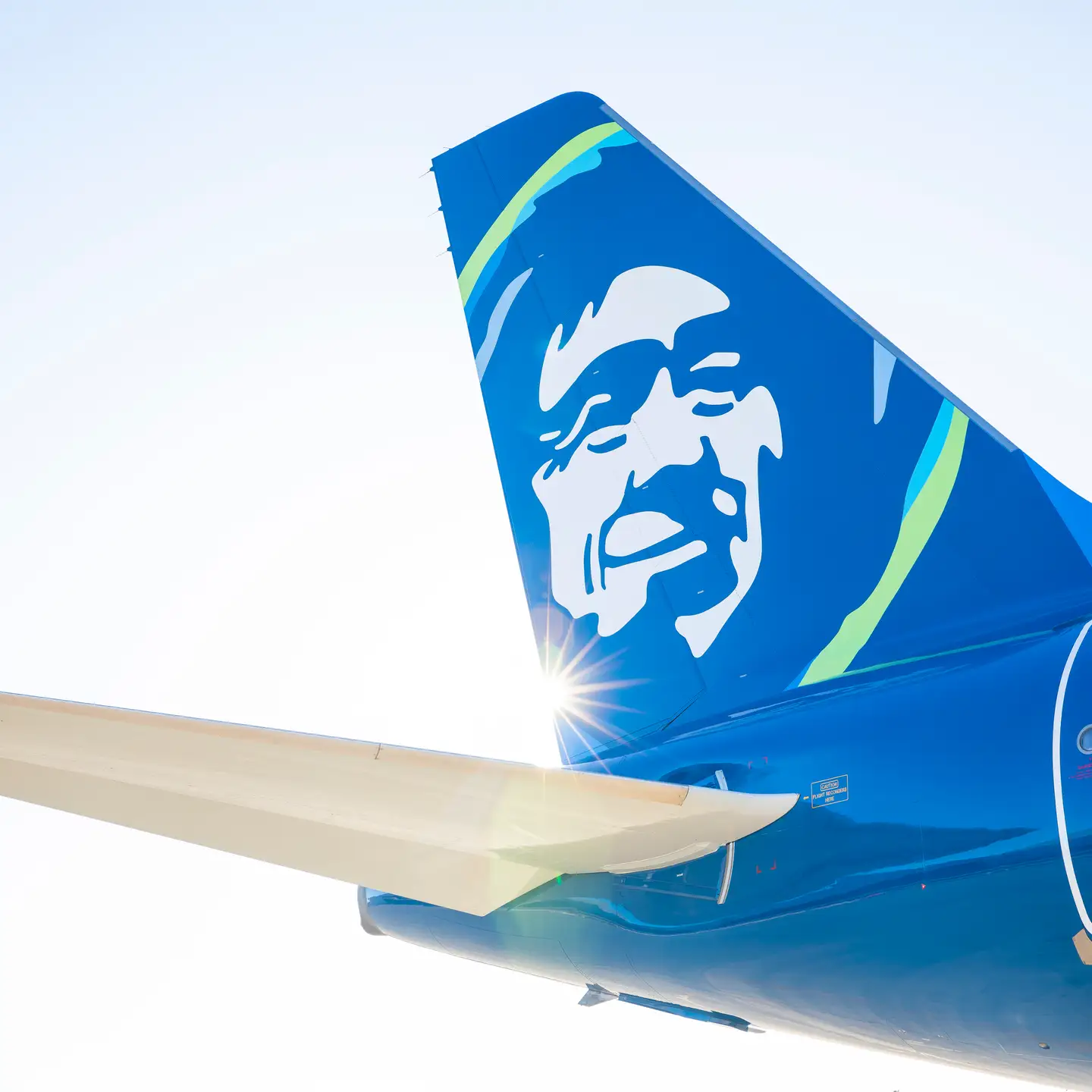 La cola de un avión de Alaska Airlines contra un cielo azul.