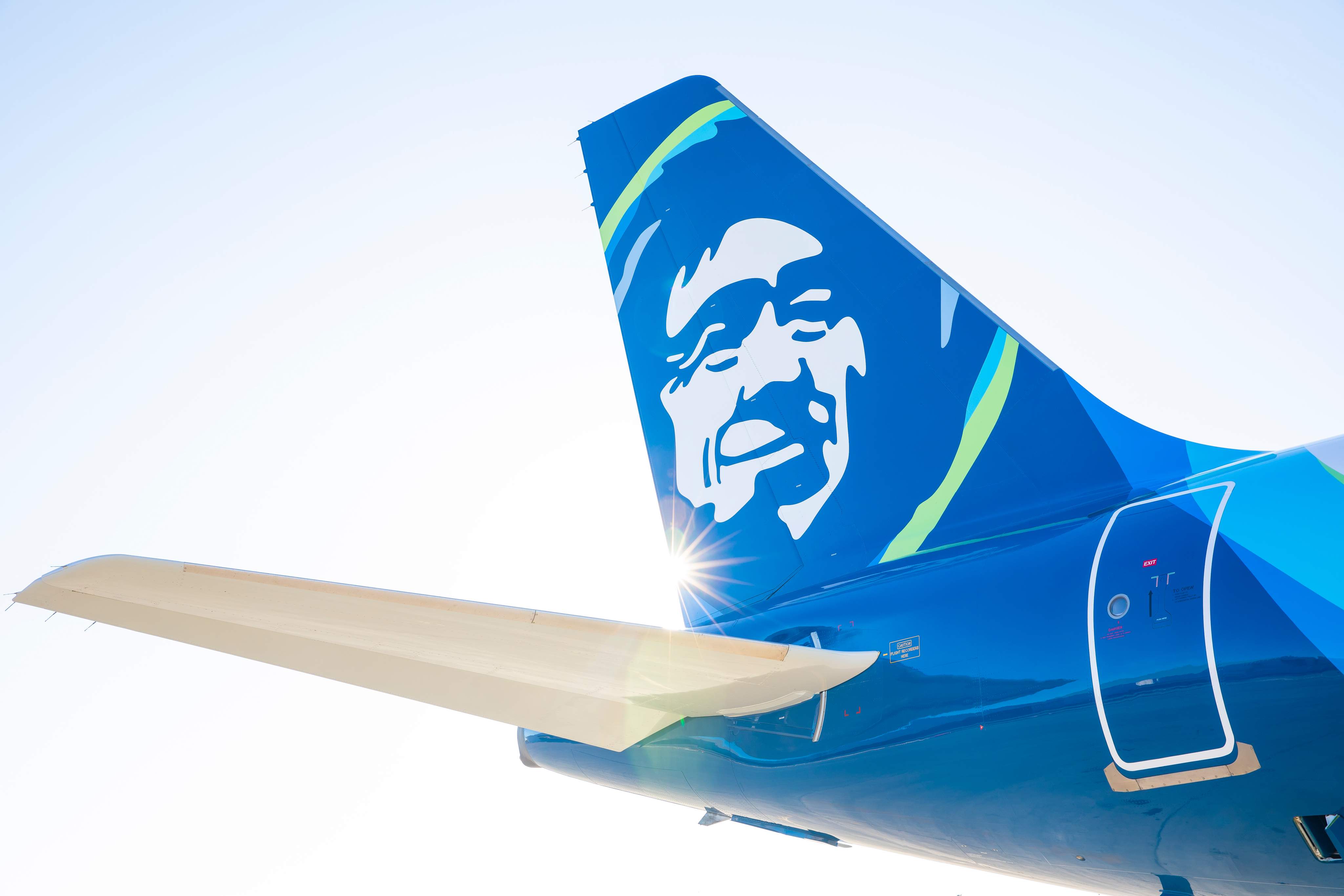 La coda di un aereo di Alaska Airlines contro un cielo blu.