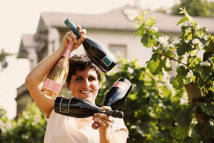 El productor de vino sostiene botellas de vino en las que el sol se refracta.