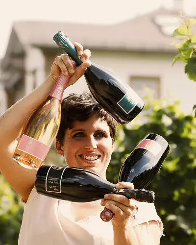 Vigneron tenant des bouteilles de vin dans lesquelles le soleil se reflète.