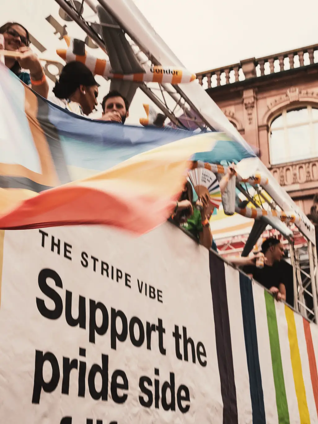 Egy színes csíkos Pride zászló, emberekkel a háttérben