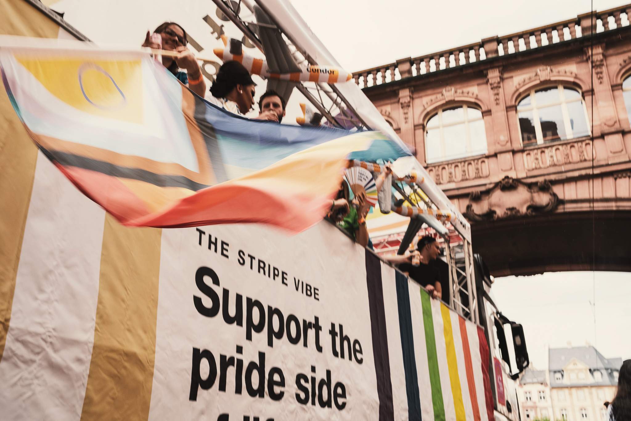 Barevná pruhovaná vlajka Pride s lidmi v pozadí